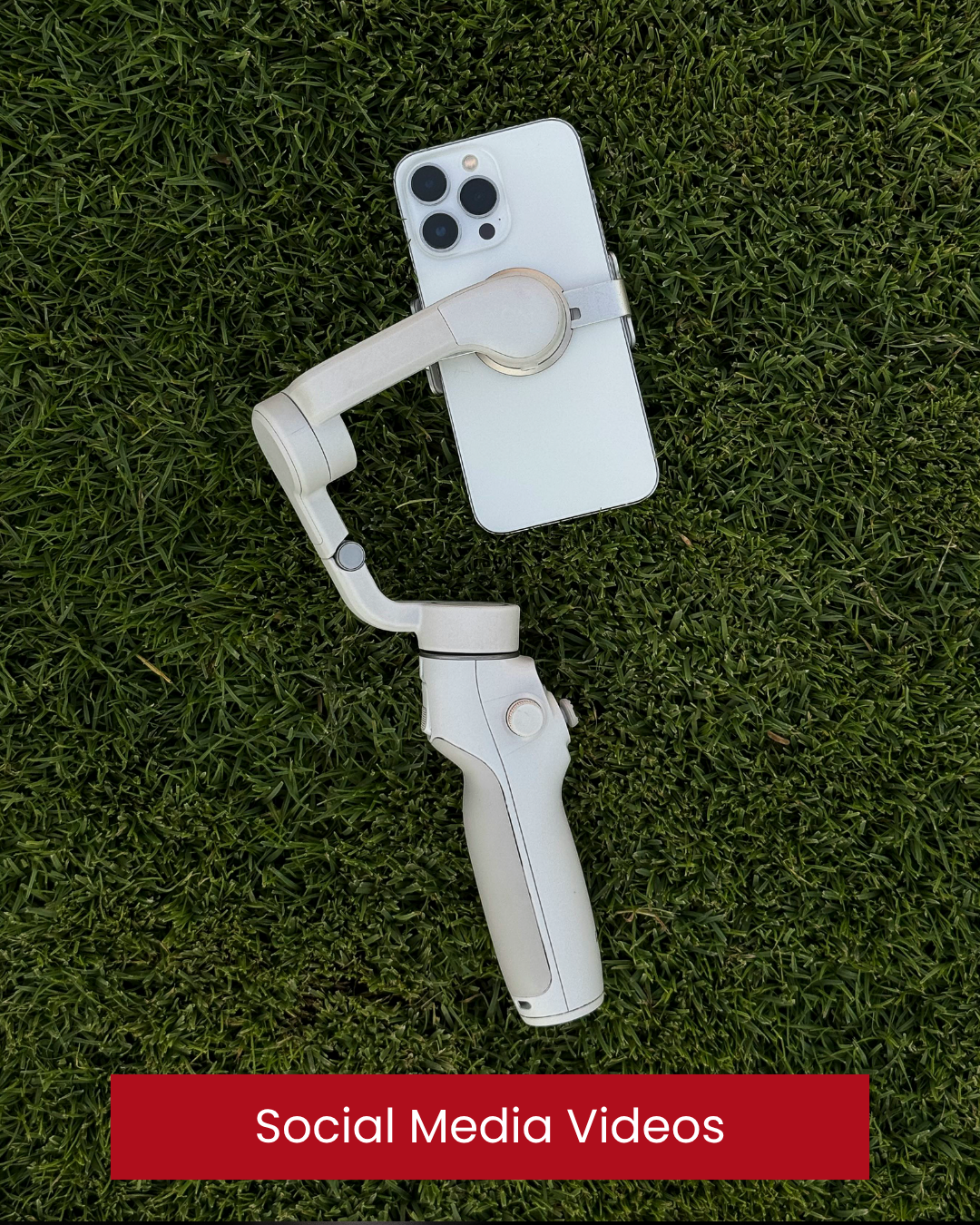 A smartphone with a gimbal stabilizer attached, lying on green grass, with a red banner at the bottom reading 'Social Media Videos'. Iphone videos. Social media content. Marketing. Donegal. Letterkenny.