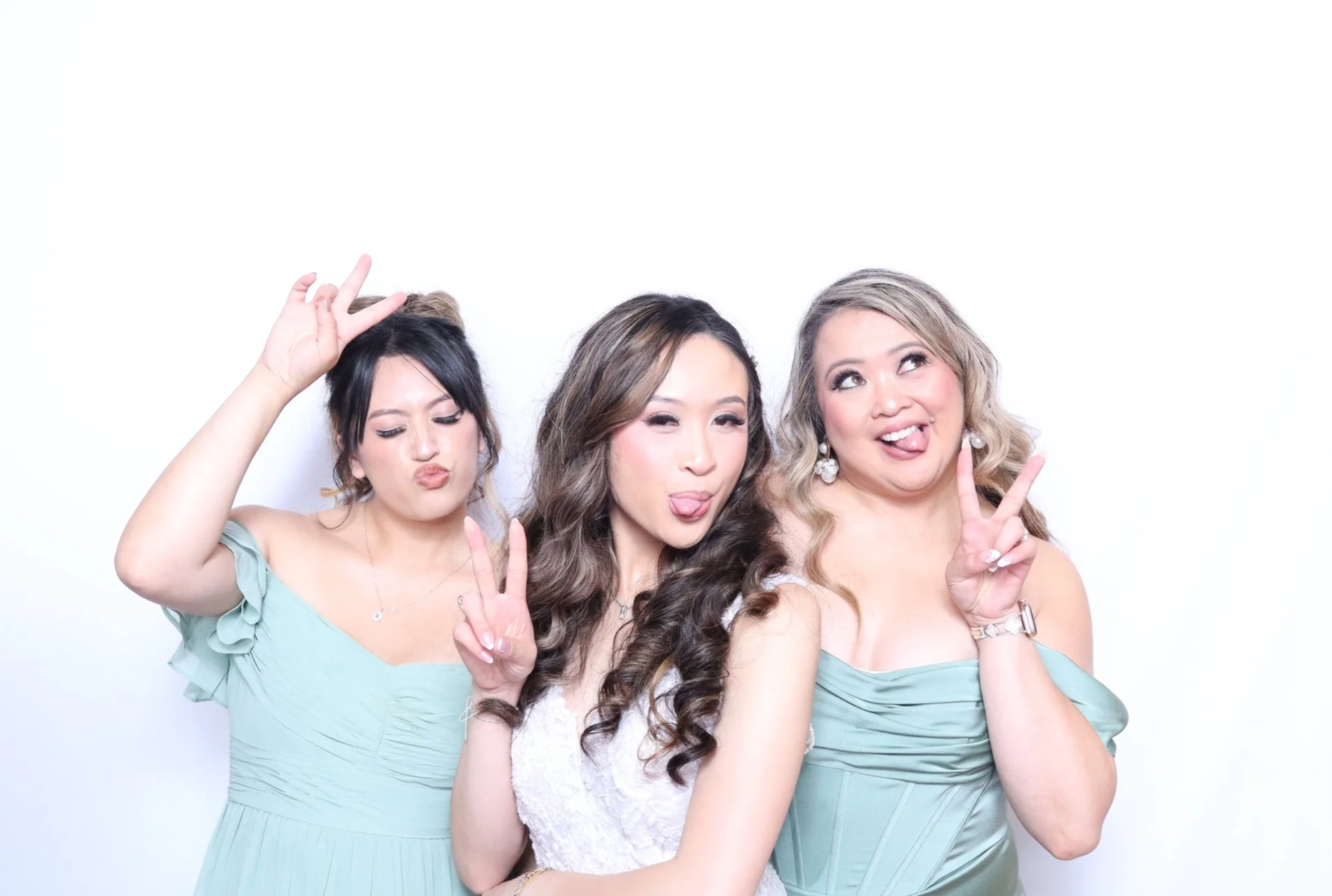 Two bridesmaids and bride posing playfully in front of a white background for the studio photo booth in Issaquah, Washington for a wedding.