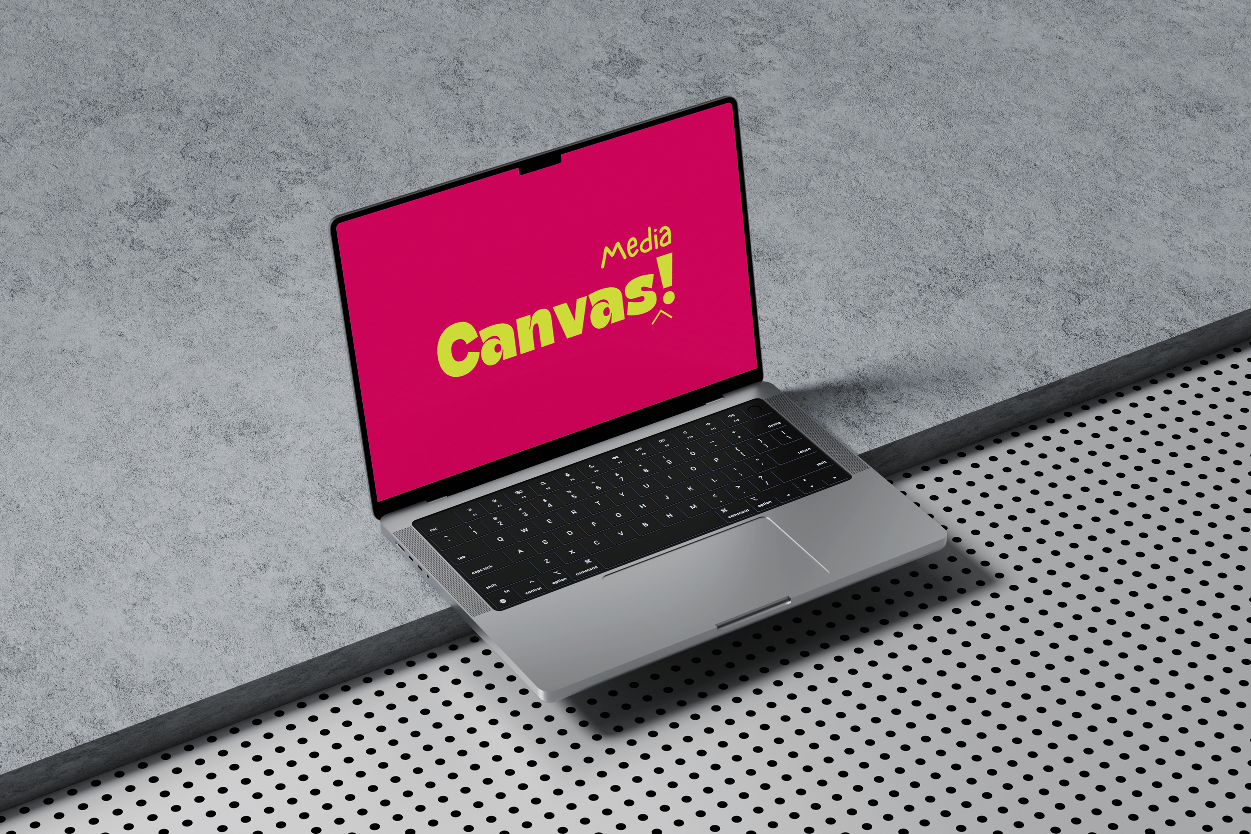 Open laptop on a desk with a pink screen displaying the text "Media Canvas!" in yellow and green.