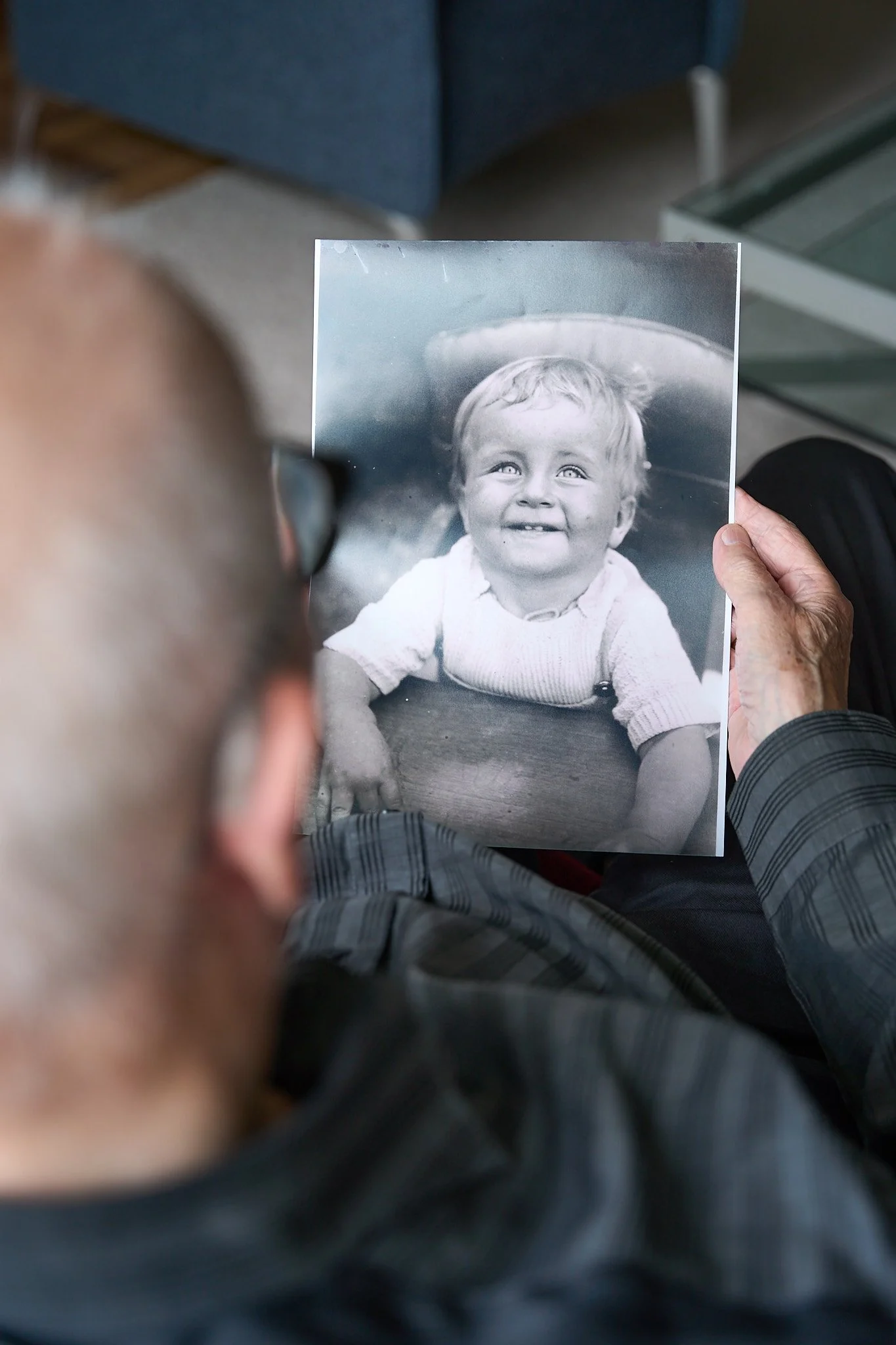 An elderly person holding a black-and-white photograph of a smiling young child.