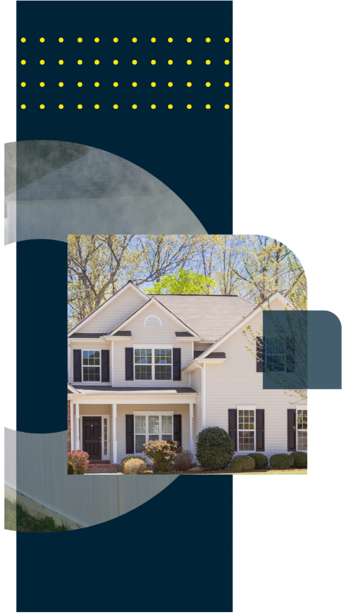 A two-story white house with black shutters and a front porch, surrounded by trees and bushes on a sunny day.