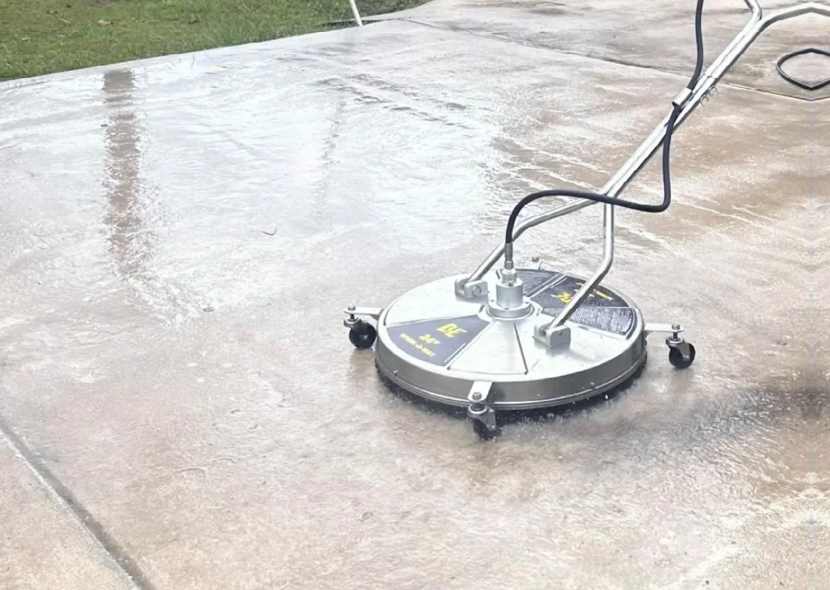 A driveway being professionally cleaned with an industrial surface cleaner.