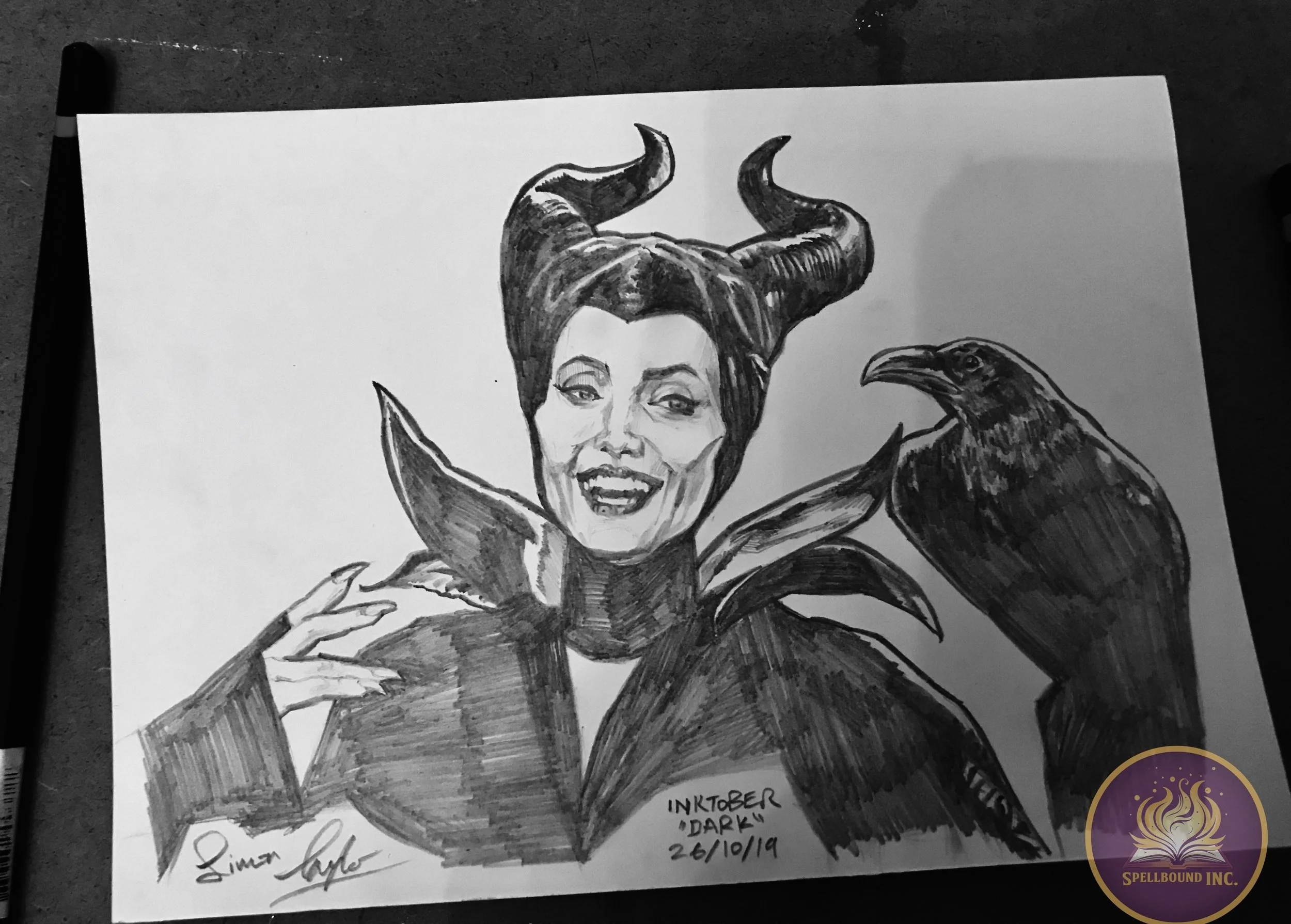 Black and white ink drawing of a woman with dark hair styled to resemble Maleficent's horns, accompanied by a raven on her shoulder, signed by the artist, with the text 'Inktober Dark 26/10/19' at the bottom right corner.