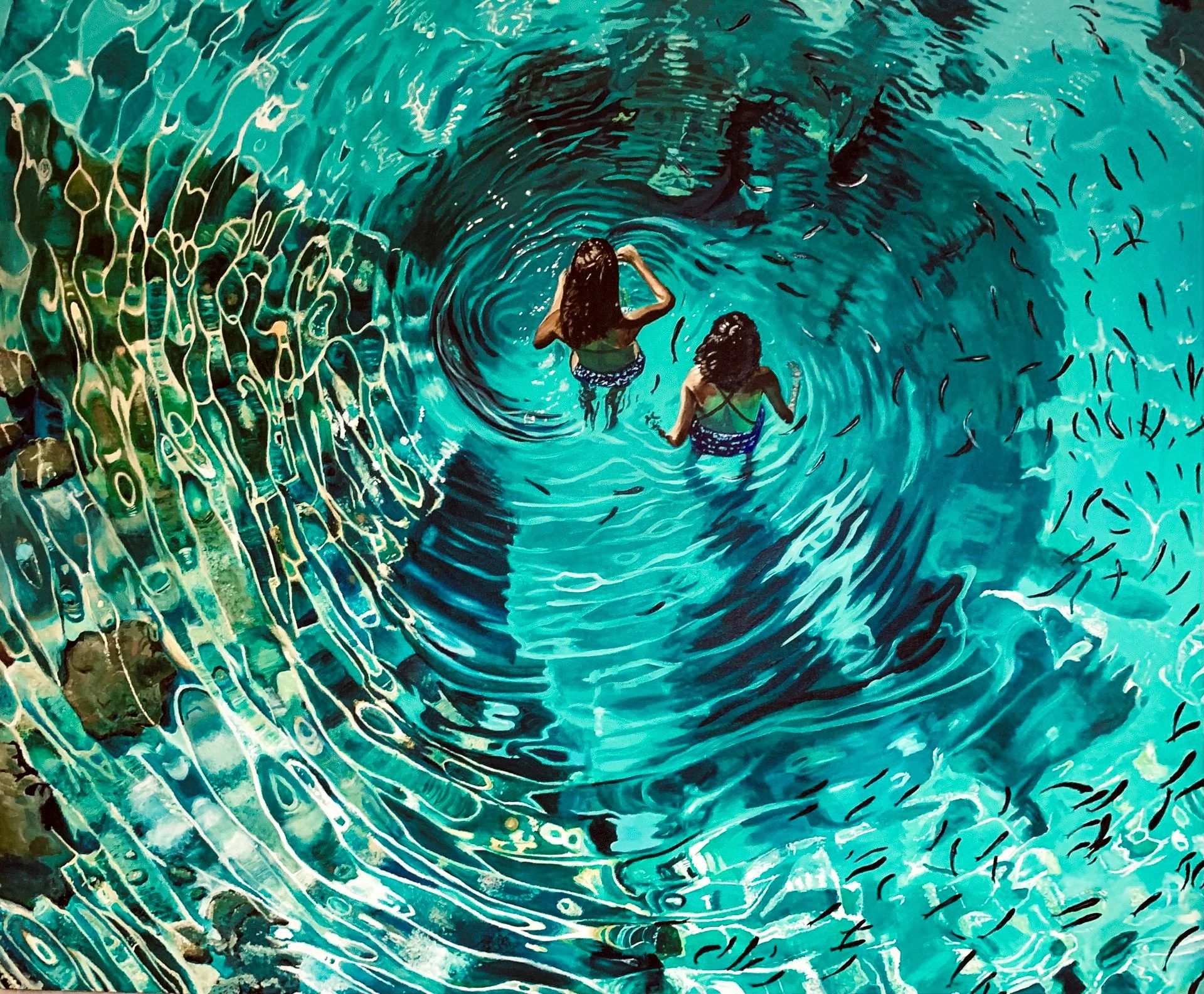 Two women in swimsuits swimming in a large, clear natural swimming pool with rippling water and rocks along the edge.