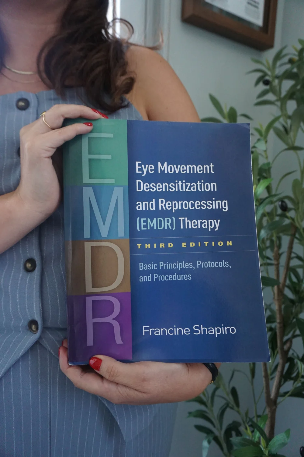 Therapist holding the EMDR therapy book by Francine Shapiro, EMDR and trauma therapy in Coral Gables, Miami