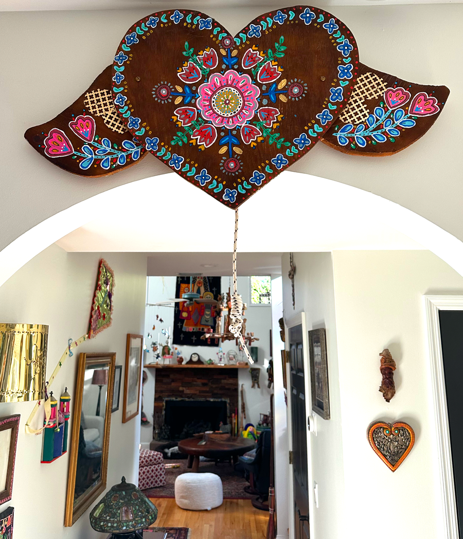 Decorative heart-shaped wooden sign with colorful floral patterns hanging above a living room entrance.
