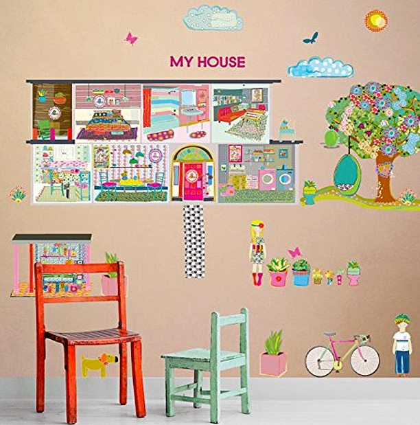 Decorative wall with a miniature house layout, colorful furniture, plants, a bicycle, a child, and outdoor scene with a tree, clouds, butterflies, and the sun.