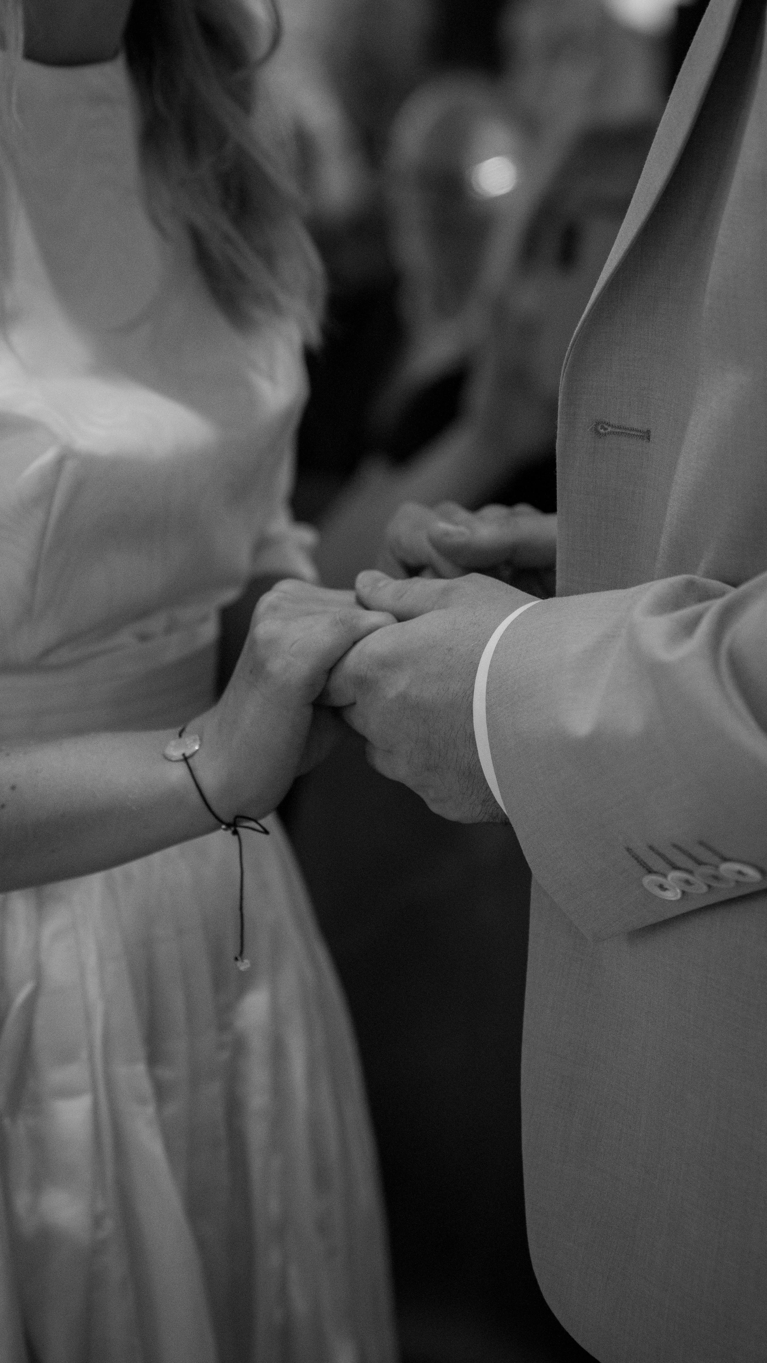 Ein Mann und eine Frau halten bei einer Hochzeit die Hände des anderen während ihrer Trauung.