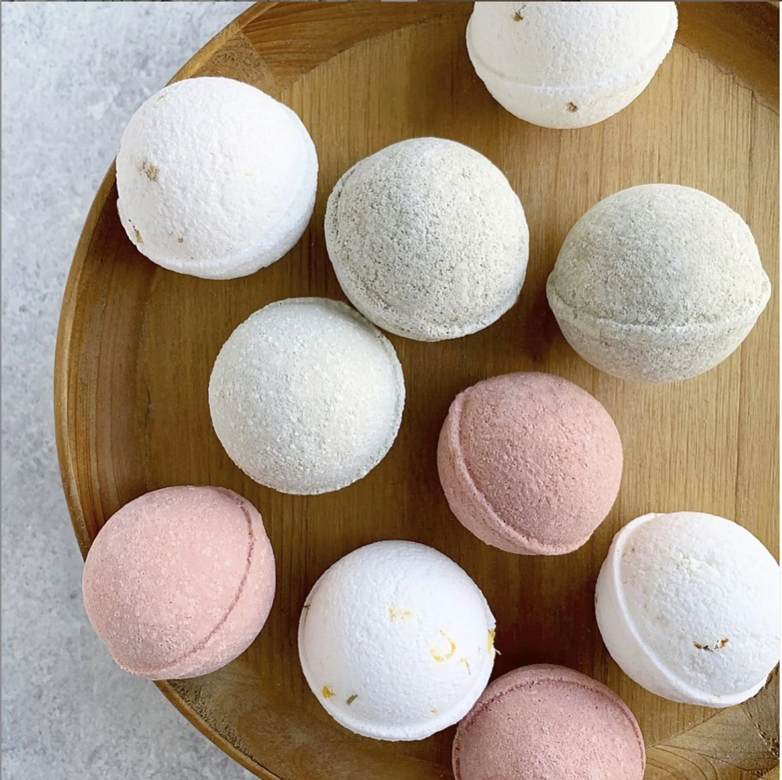 Colorful bath bombs arranged on a wooden tray with soft natural lighting.