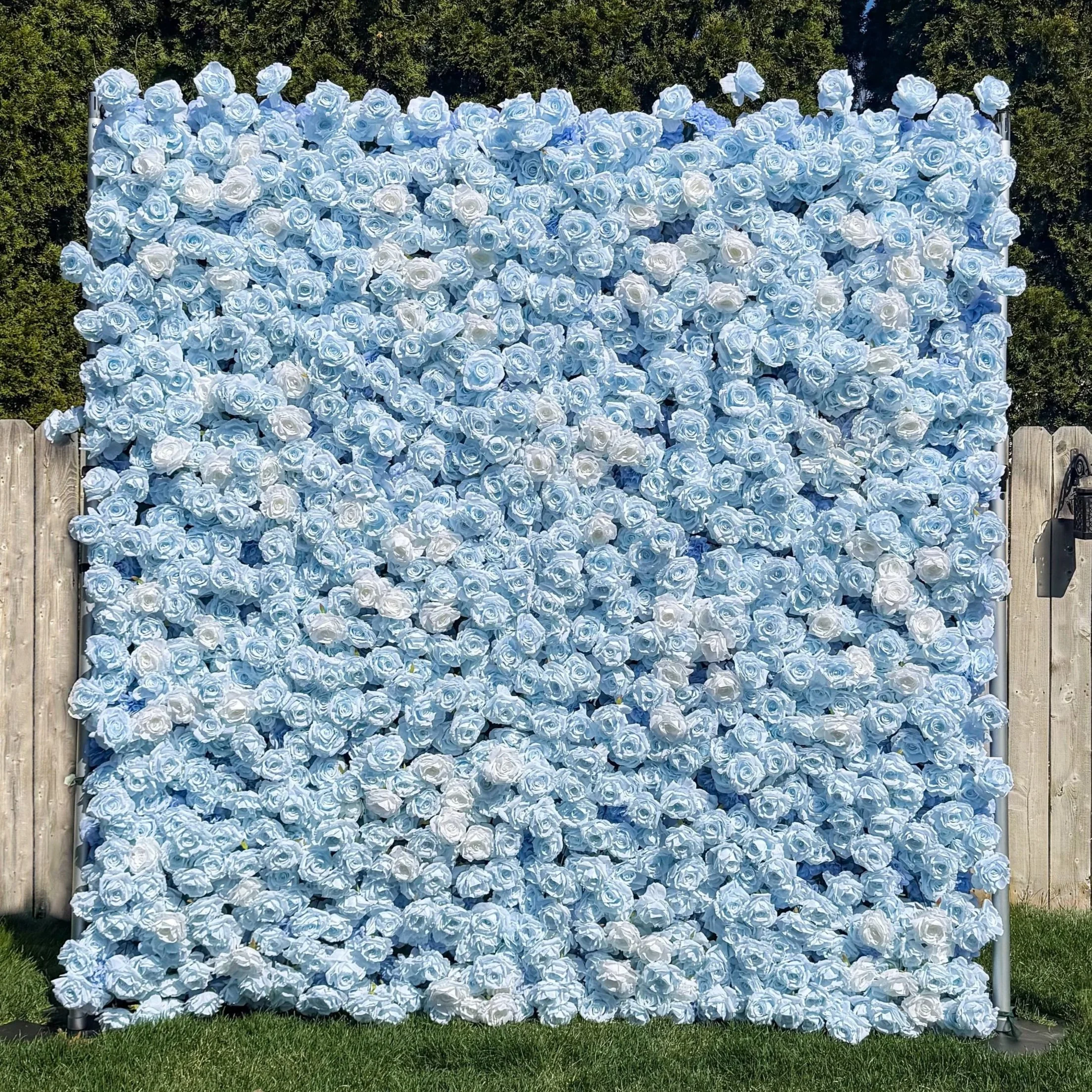 A large outdoor display of many white and light blue roses arranged on a wall or panel.