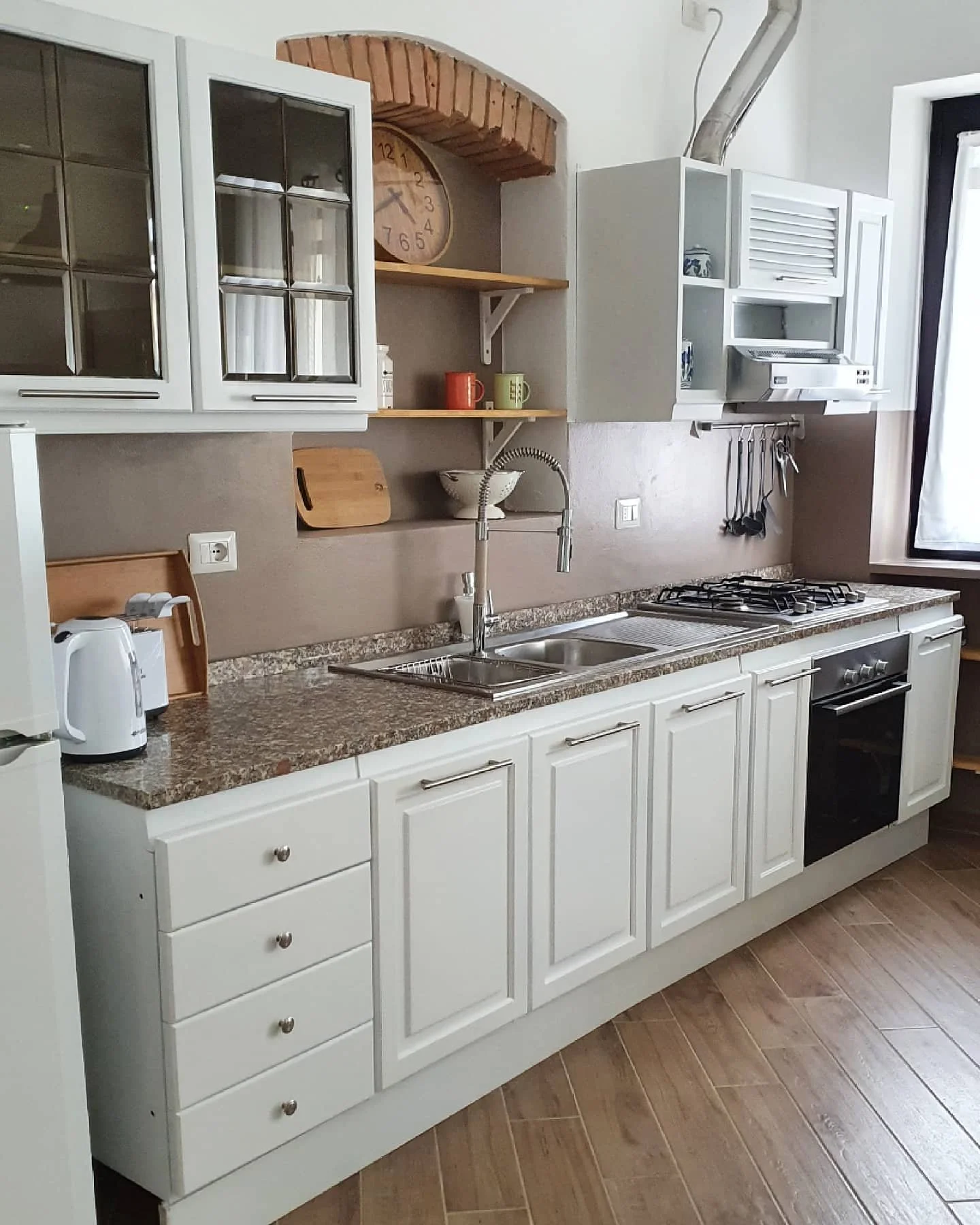 Cucina con mobili bianchi, piano cucina in marmo, completamente rinnovata