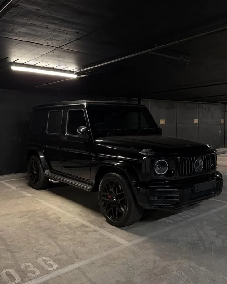 Black Mercedes-Benz G-Class SUV parked in a dimly lit underground parking garage.