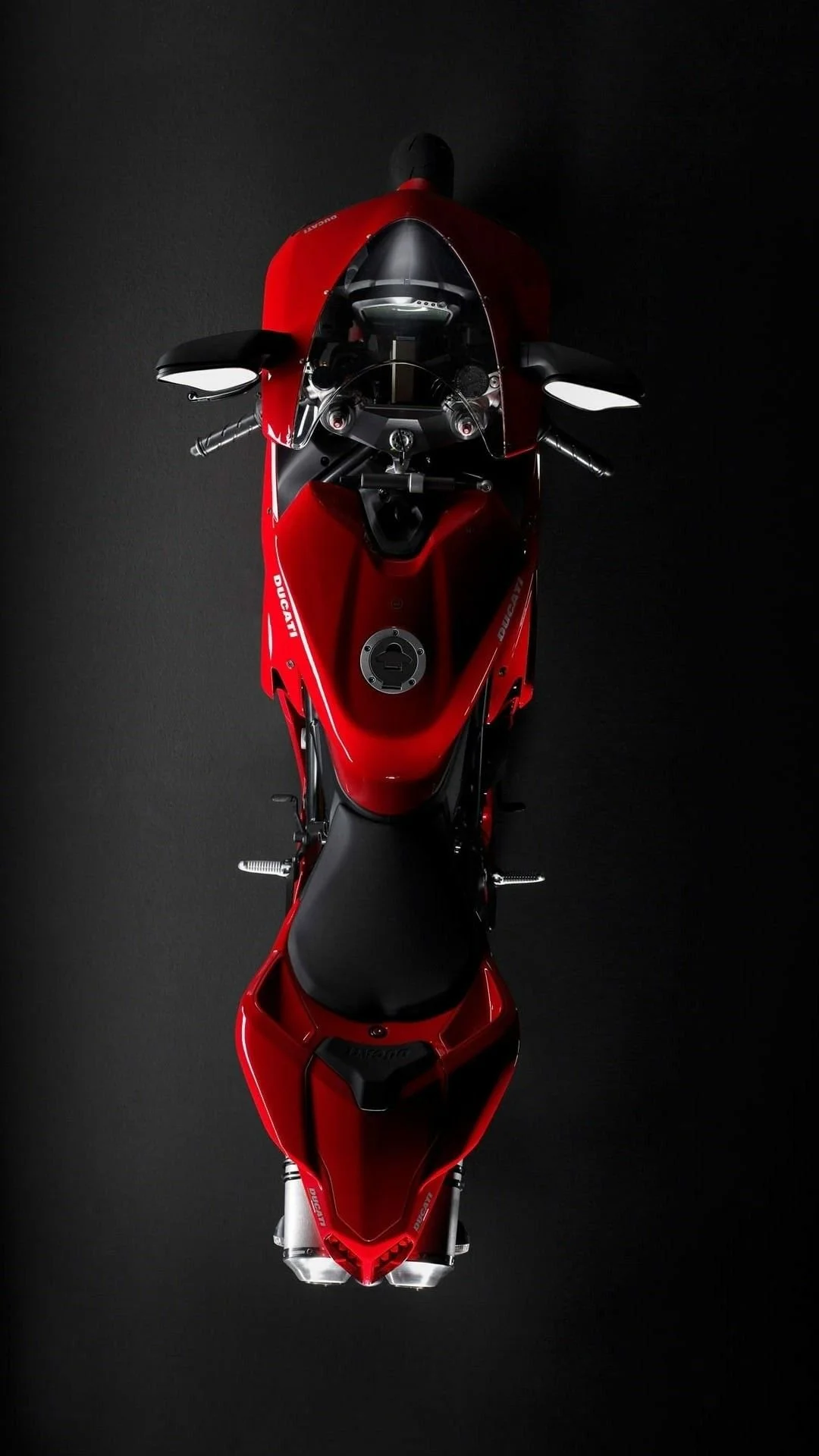 Top view of a red Ducati sport motorcycle on a black surface.