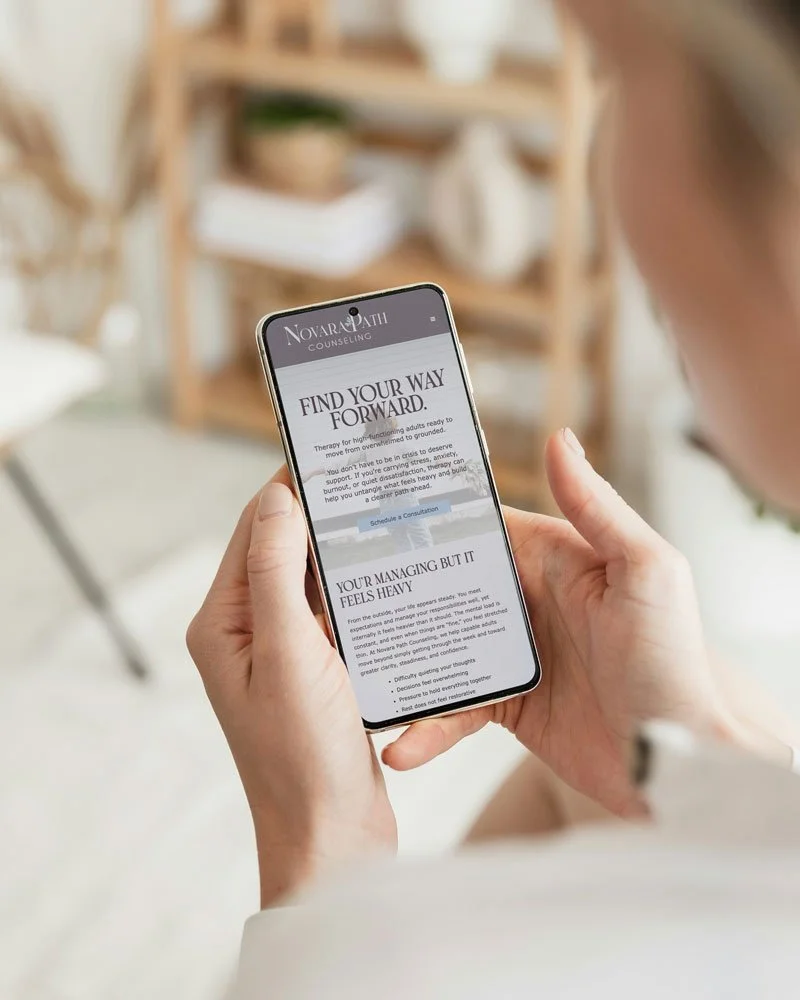 Person holding a smartphone indoors, viewing a counseling service webpage.