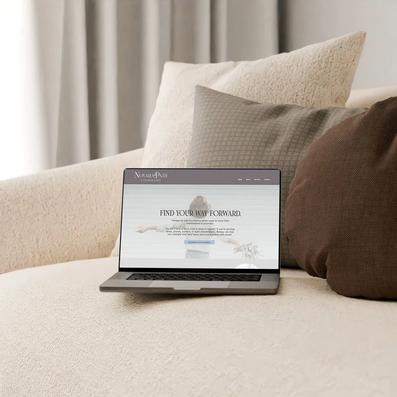 Laptop on a beige couch displaying a website called Nova Palm Counseling with the message 'Find Your Way Forward'.