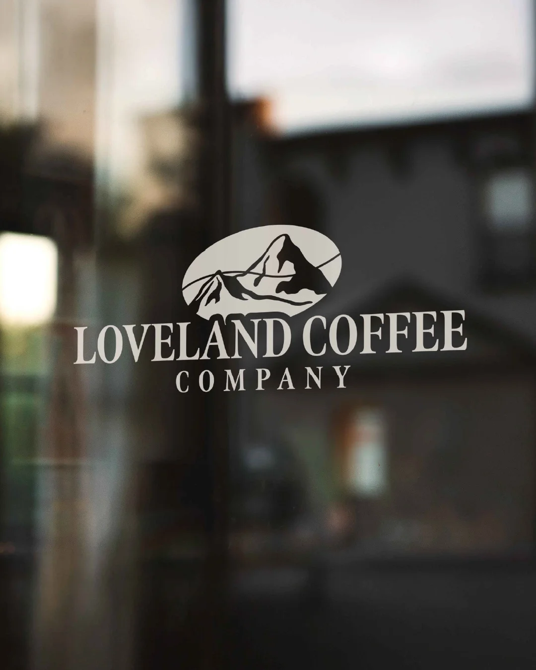 Logo for Loveland Coffee Company featuring a mountain range illustration on a glass door.