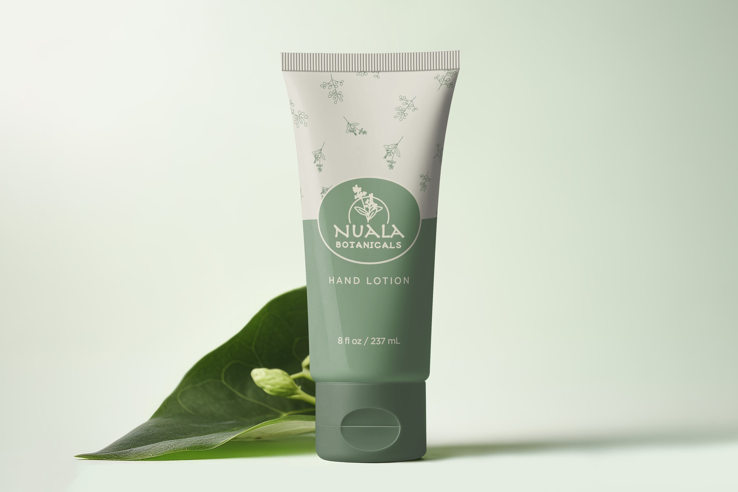 A tube of Nuala Botanicals hand lotion placed on a green leaf with a soft, pale background.