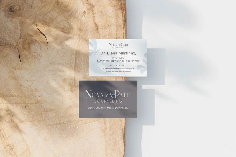 Two business cards on a wooden surface; one for Dr. Elena Martinez, a licensed professional counselor, and another for Novara Path Counseling with the tagline "Clarity. Structure. Meaningful Change."