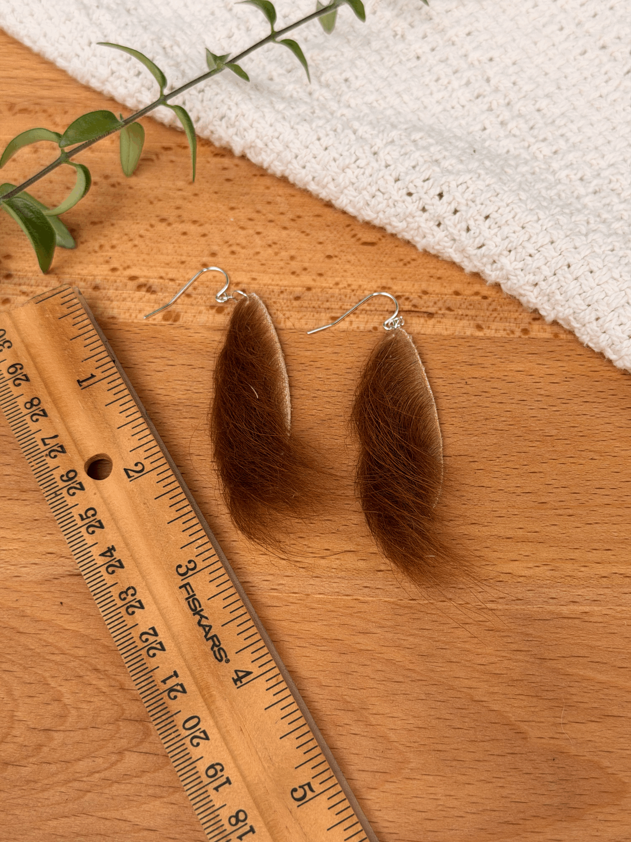 Wispy teardrop earrings depicted next to a ruler to show size