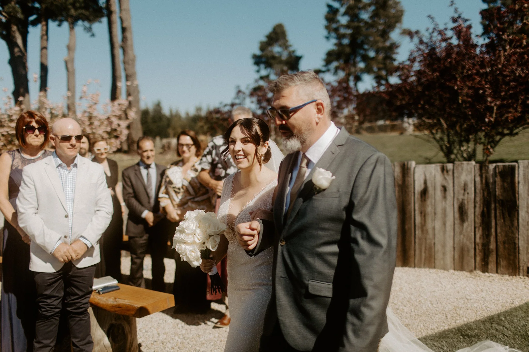 Bride entering outdoor wedding ceremony with father while guests watch at Seclusions Blue Mountains.