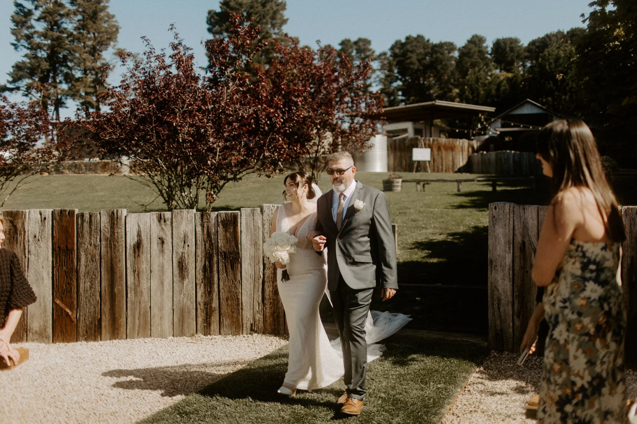 Bride entering outdoor wedding ceremony with father while guests watch at Seclusions Blue Mountains.