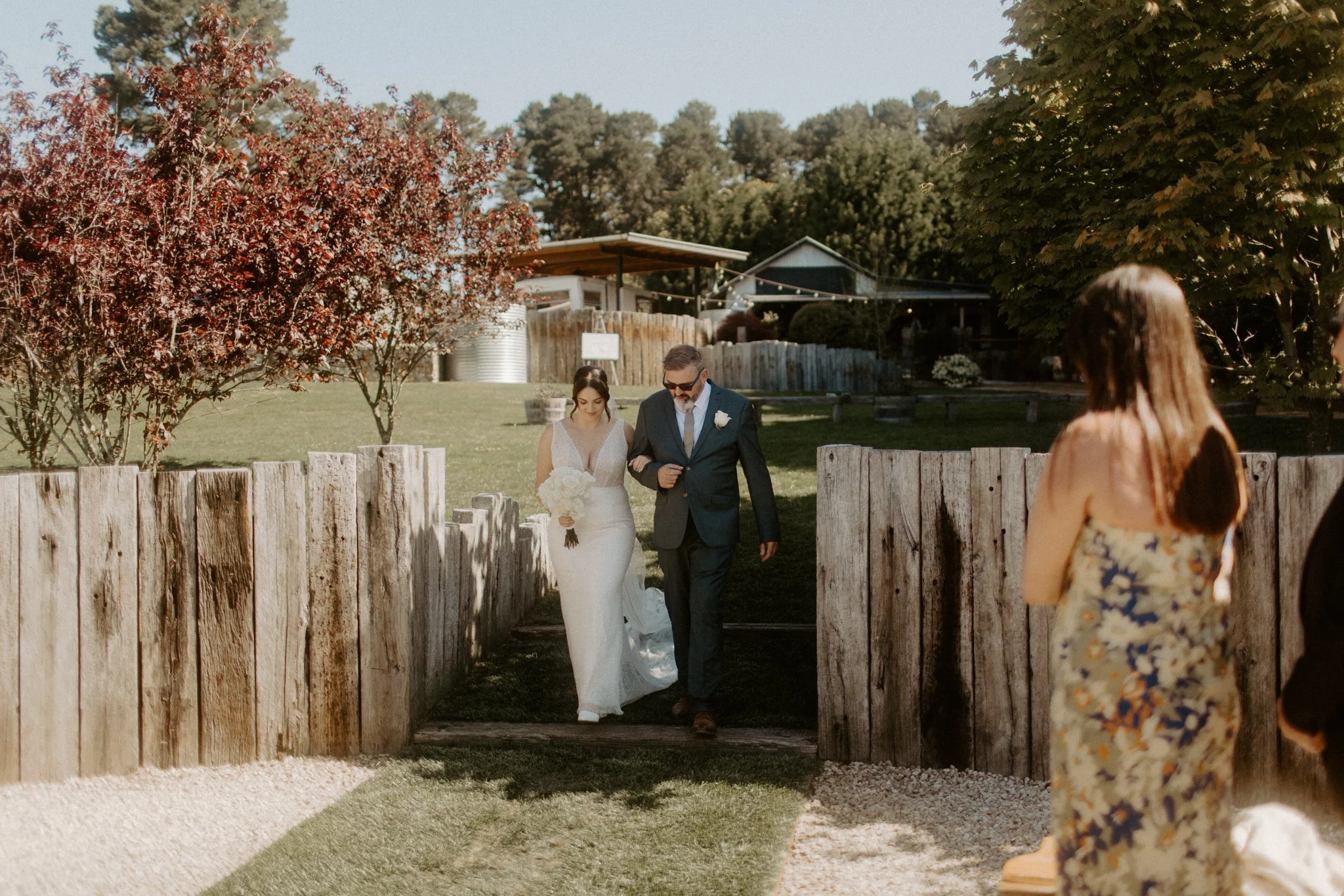 Bride entering outdoor wedding ceremony with father while guests watch at Seclusions Blue Mountains.