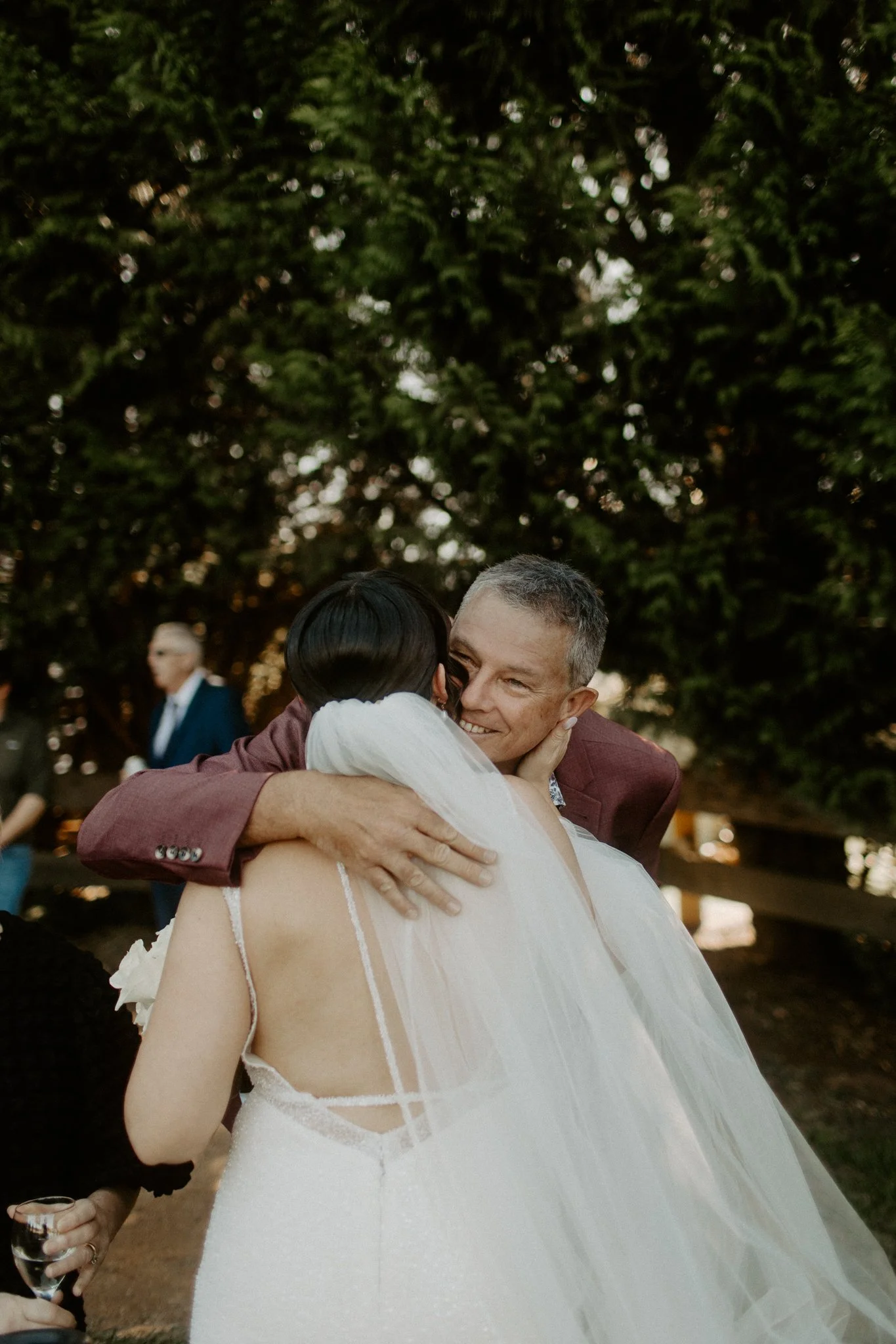 A bride and groom sharing a joyful hug outdoors during their wedding celebration.