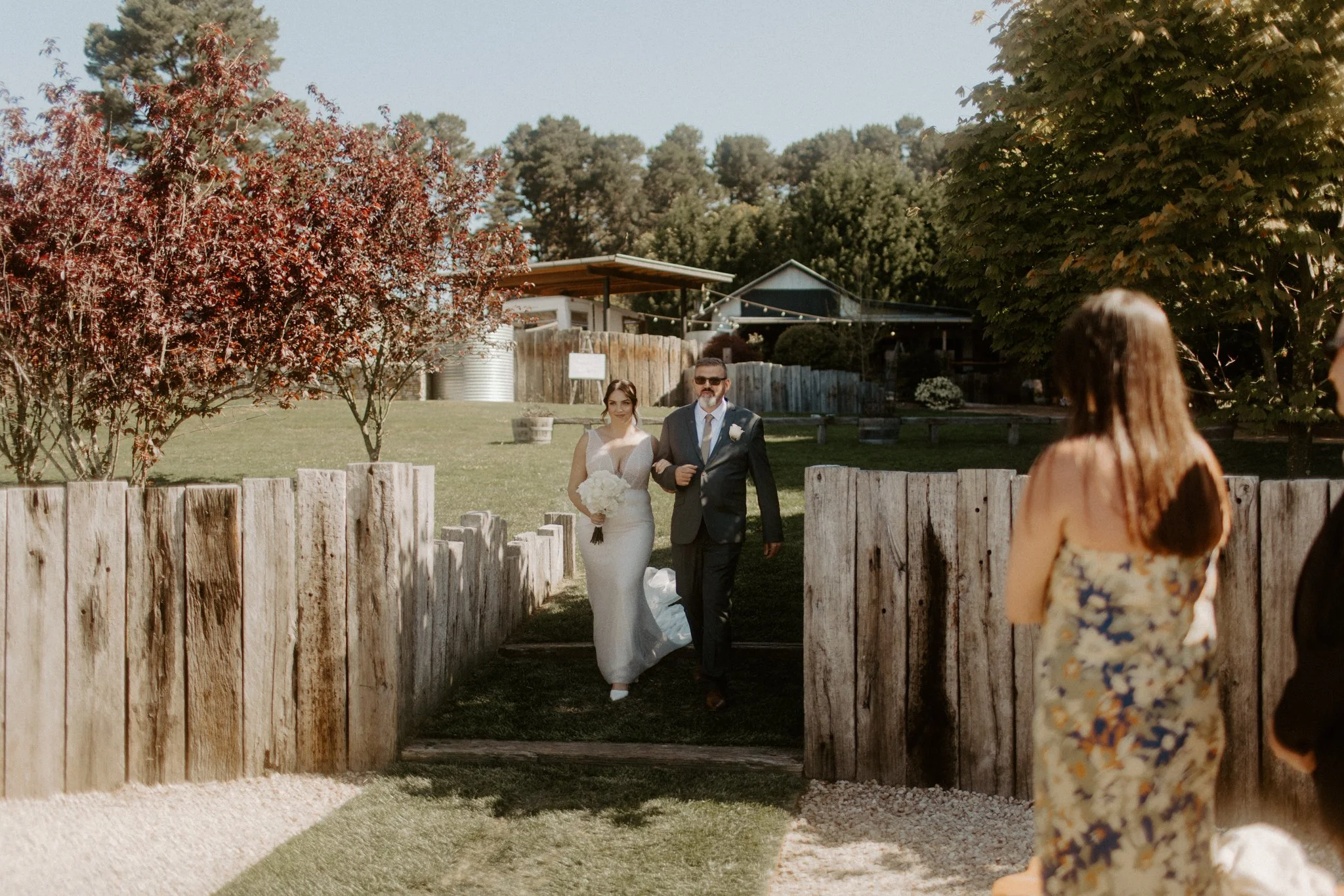 Bride entering outdoor wedding ceremony with father while guests watch at Seclusions Blue Mountains.