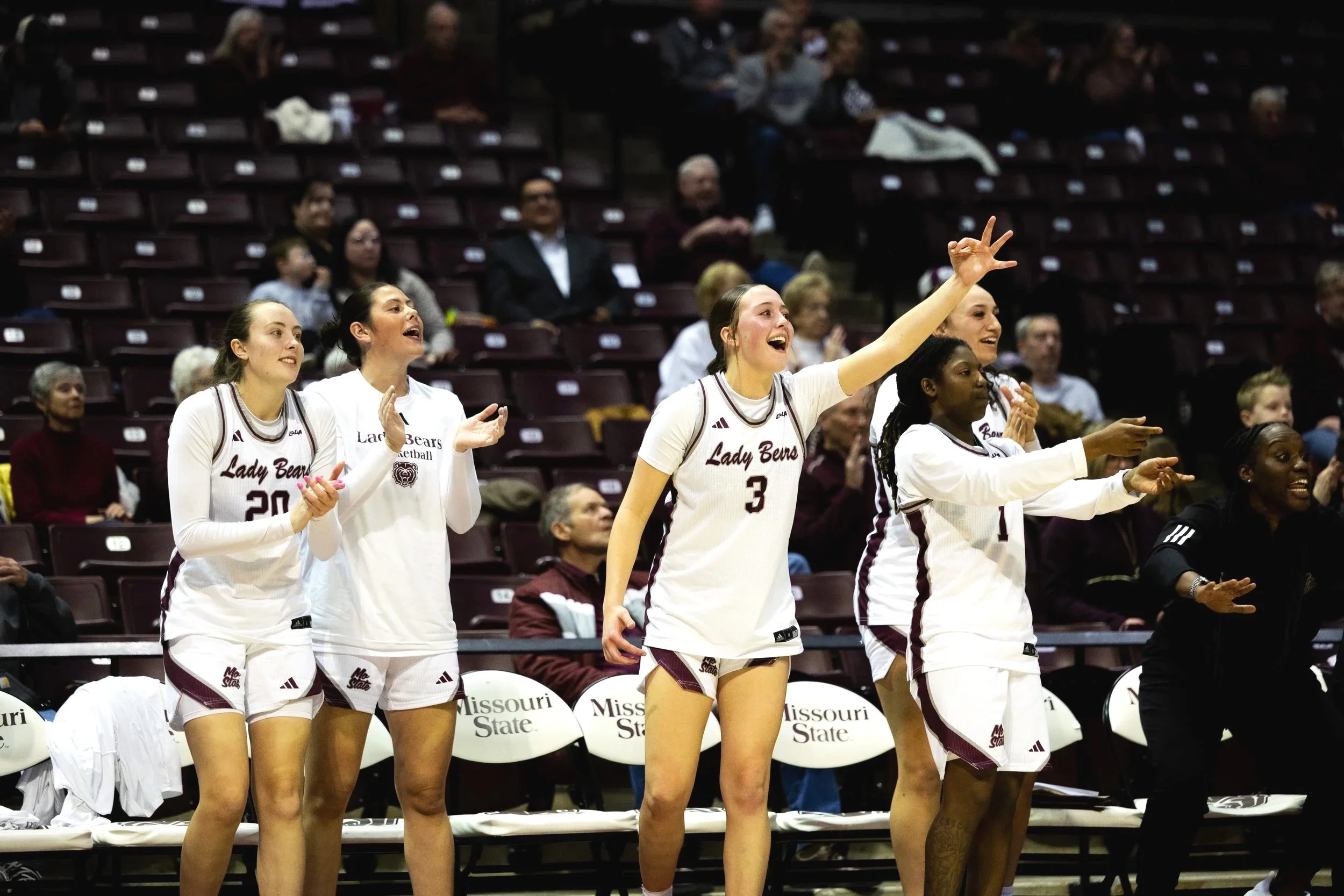 Lady Bears basketball players cheering from the bench during a game at Missouri State.