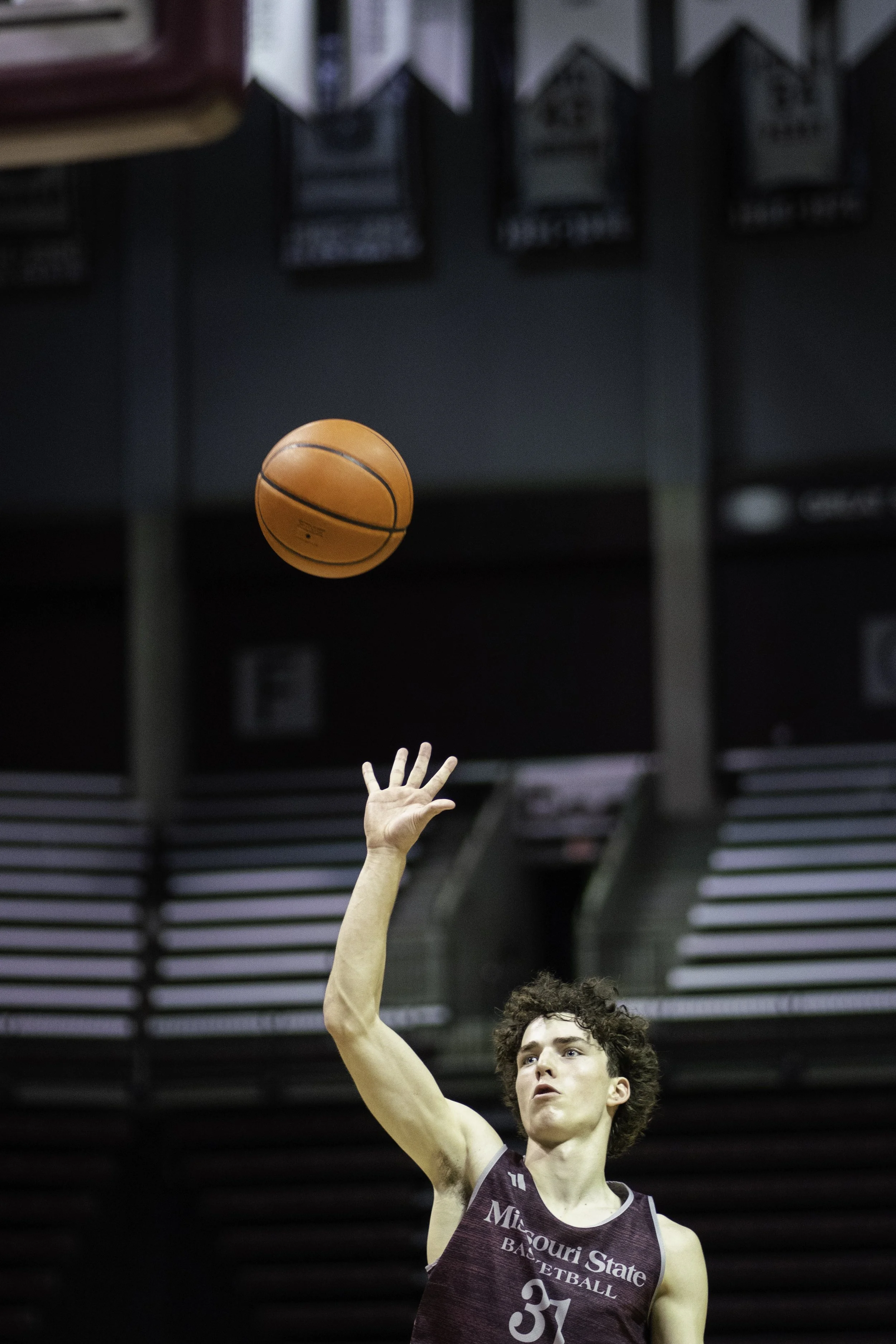 A young male basketball player wearing a Missouri State basketball uniform with the number 31, reaching up with his right hand to shoot a basketball inside an indoor basketball court.