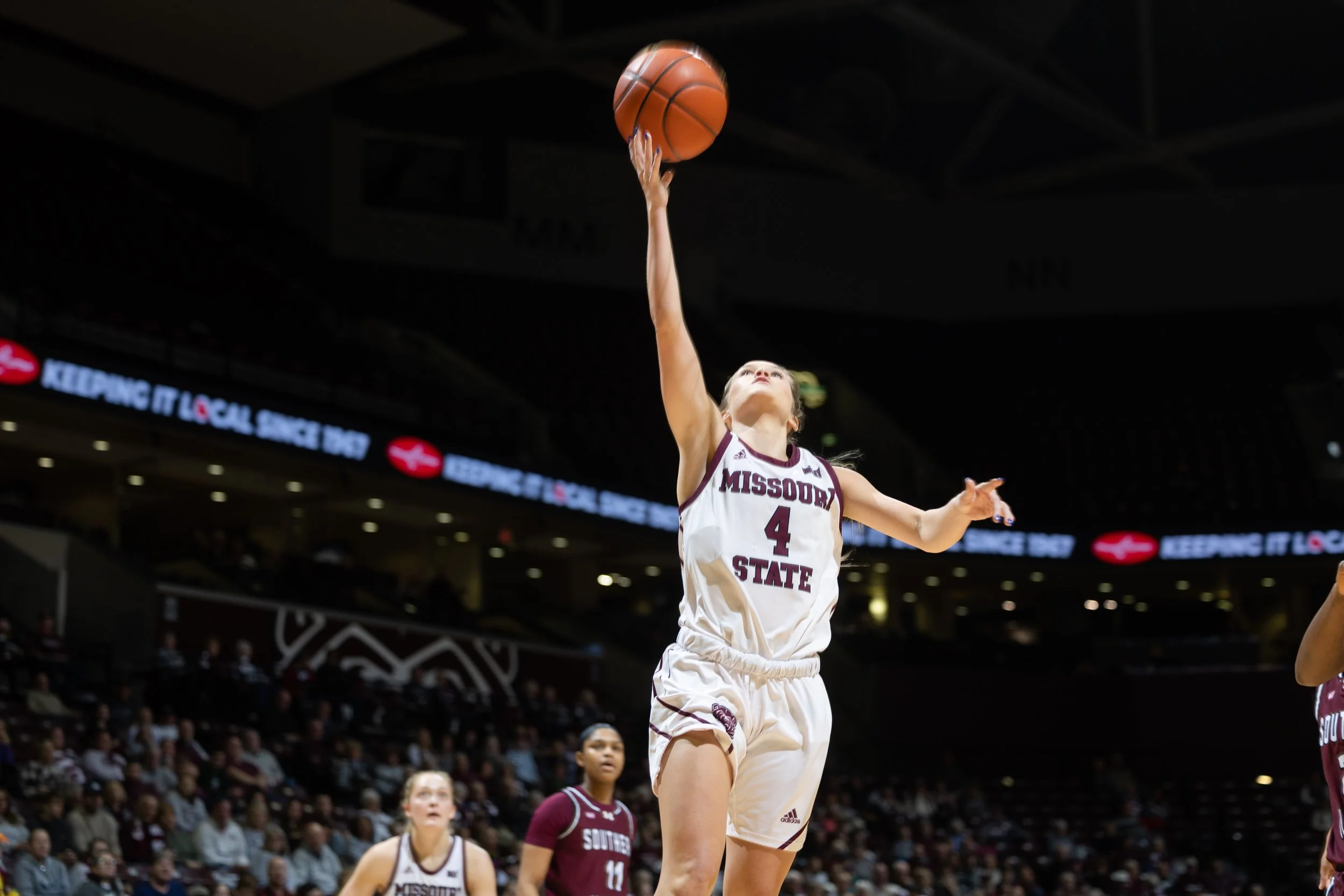 A female basketball player from Missouri State wearing jersey number 4 is jumping to shoot a basketball towards the hoop during a game.