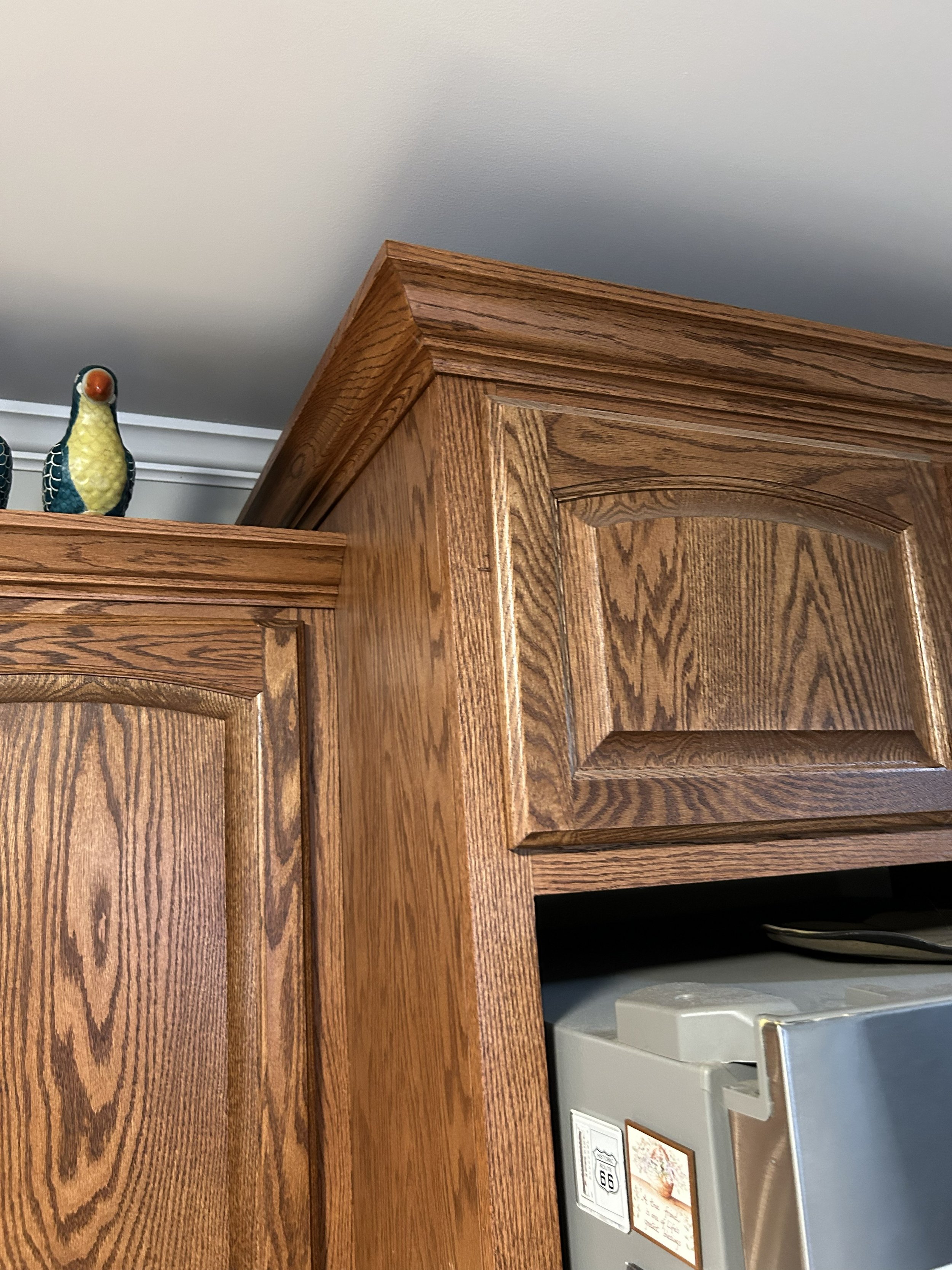 Close-up of wooden kitchen cabinets with decorative ceramic bird figurines on top.