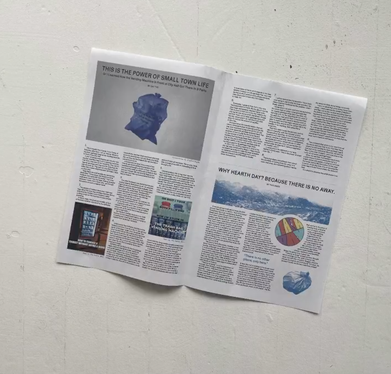 A newspaper spread laid on a white surface, featuring various articles, images, and headlines, including one about small town life and Earth Day.