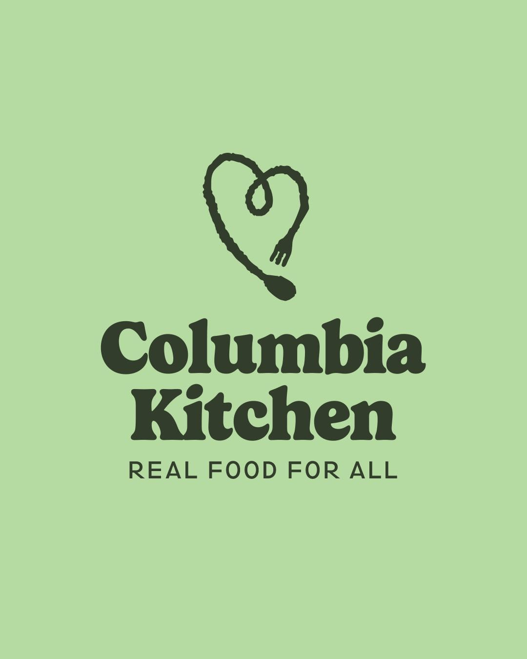 Green background with a black line drawing of a heart shaped fork and spoon above the text 'Columbia Kitchen' and the slogan 'Real Food for All'.