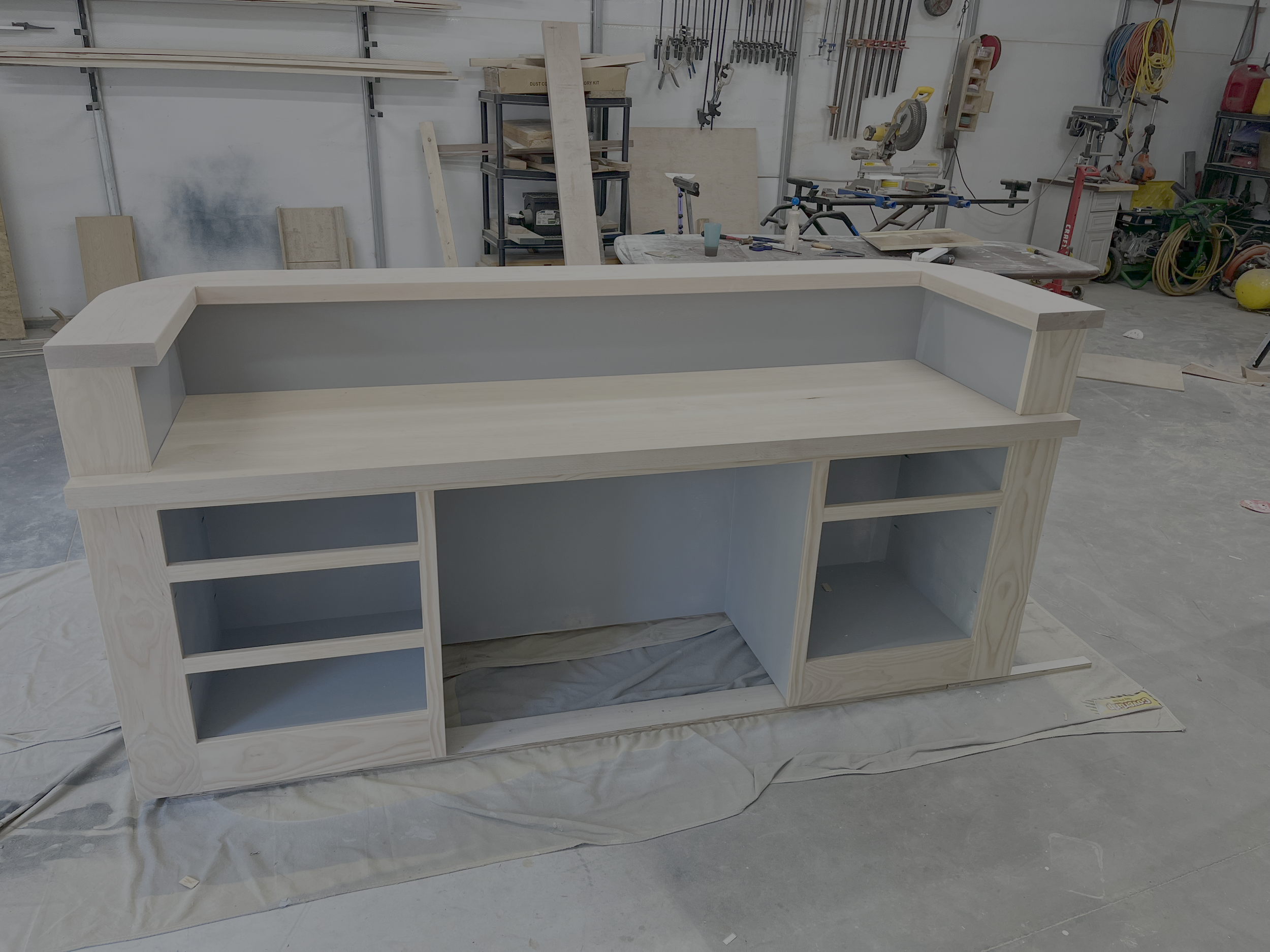 unfinished wooden cabinet with open shelves in a woodworking shop.