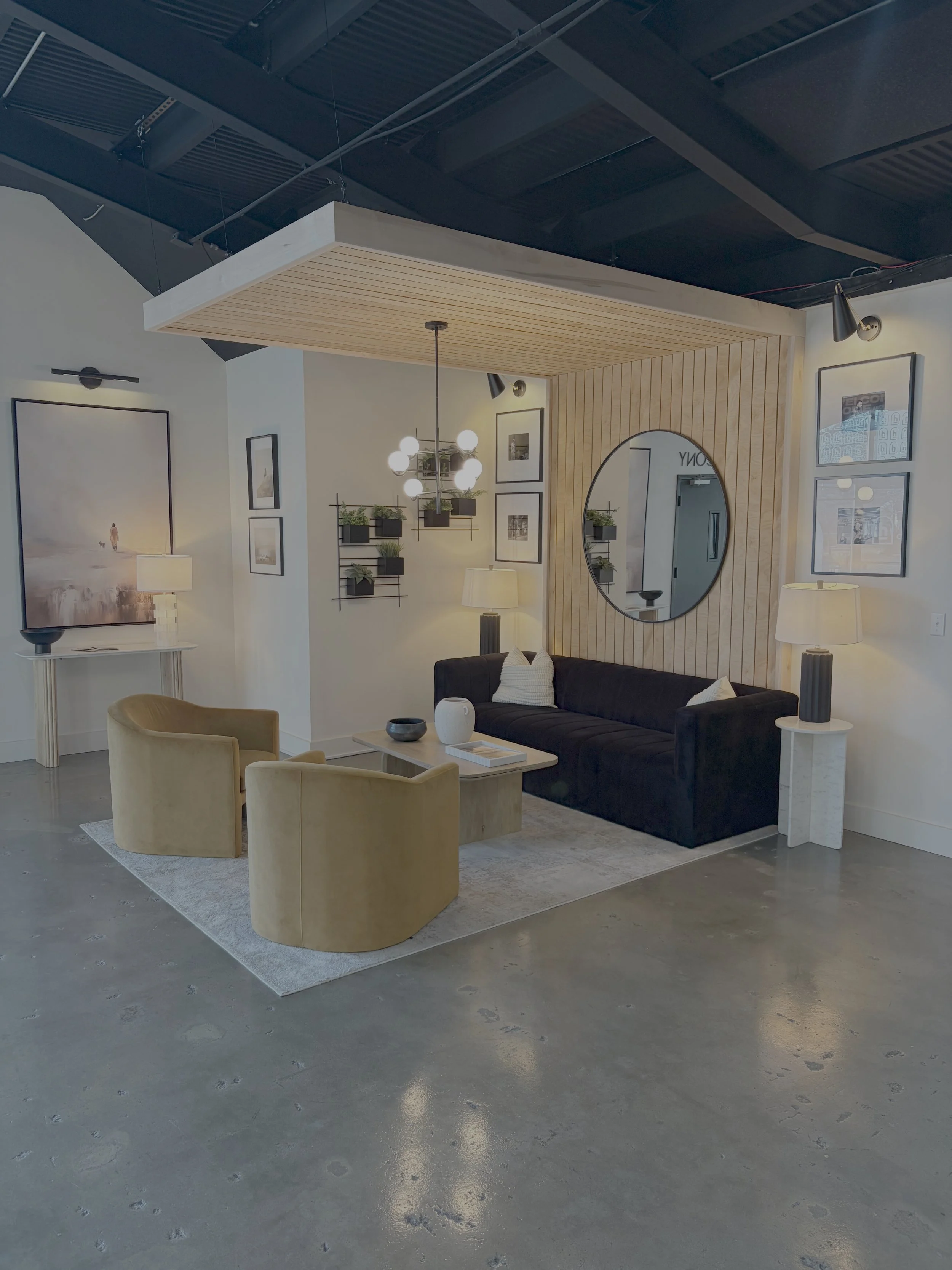 Modern living room with black sofa, beige armchairs, wooden accents, and artwork on the walls.