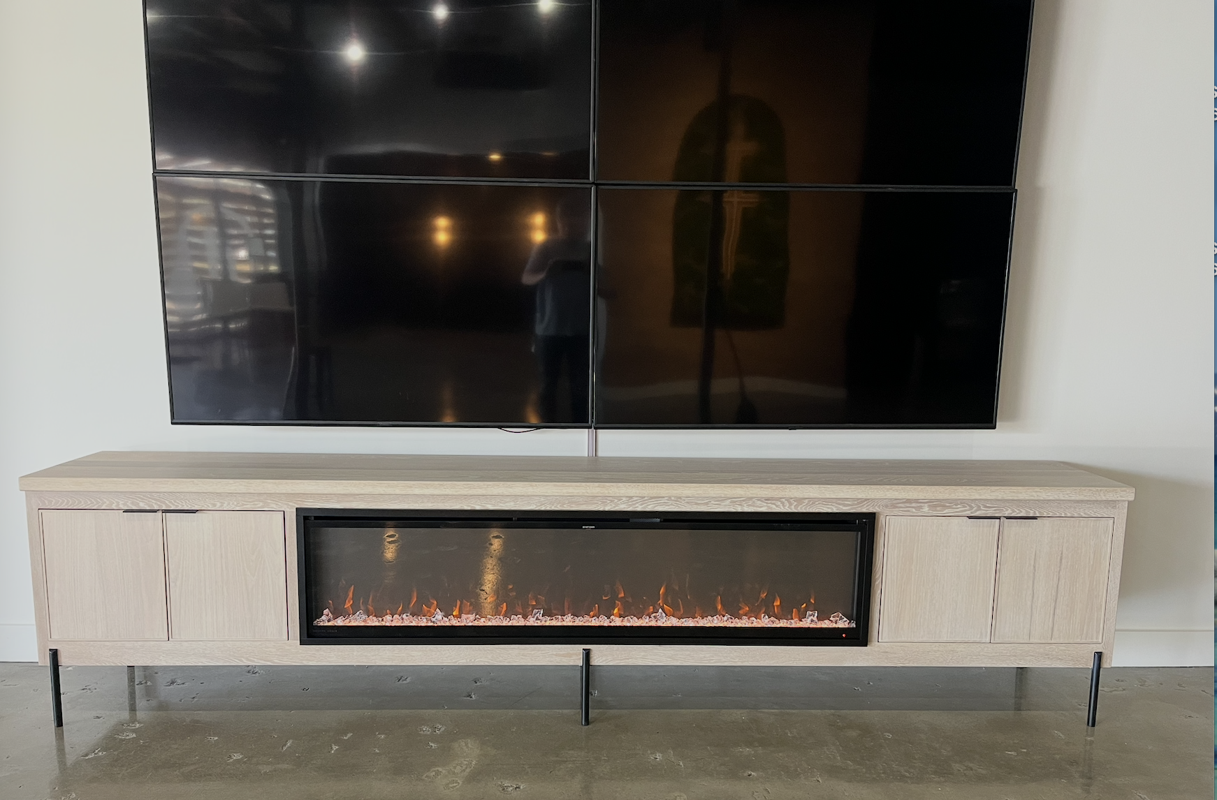 Modern entertainment console with a mounted flat-screen TV and an electric fireplace.