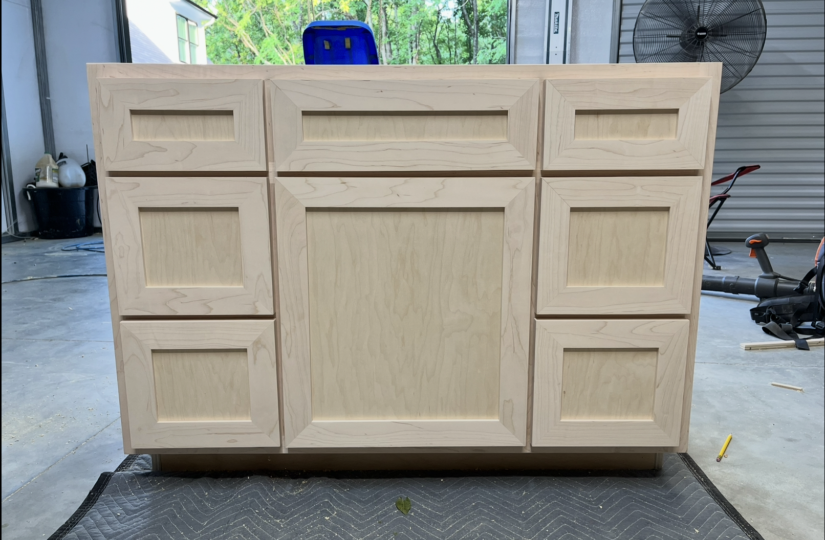 Unfinished wooden cabinet with nine panels in a workshop.