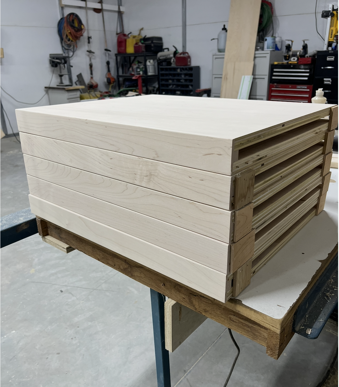 Stack of unfinished wooden planks on a workbench in a woodworking shop.