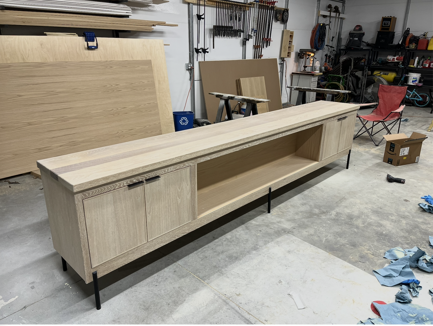 Wooden TV stand with cabinet doors on the left and open space in the center, in a workshop.