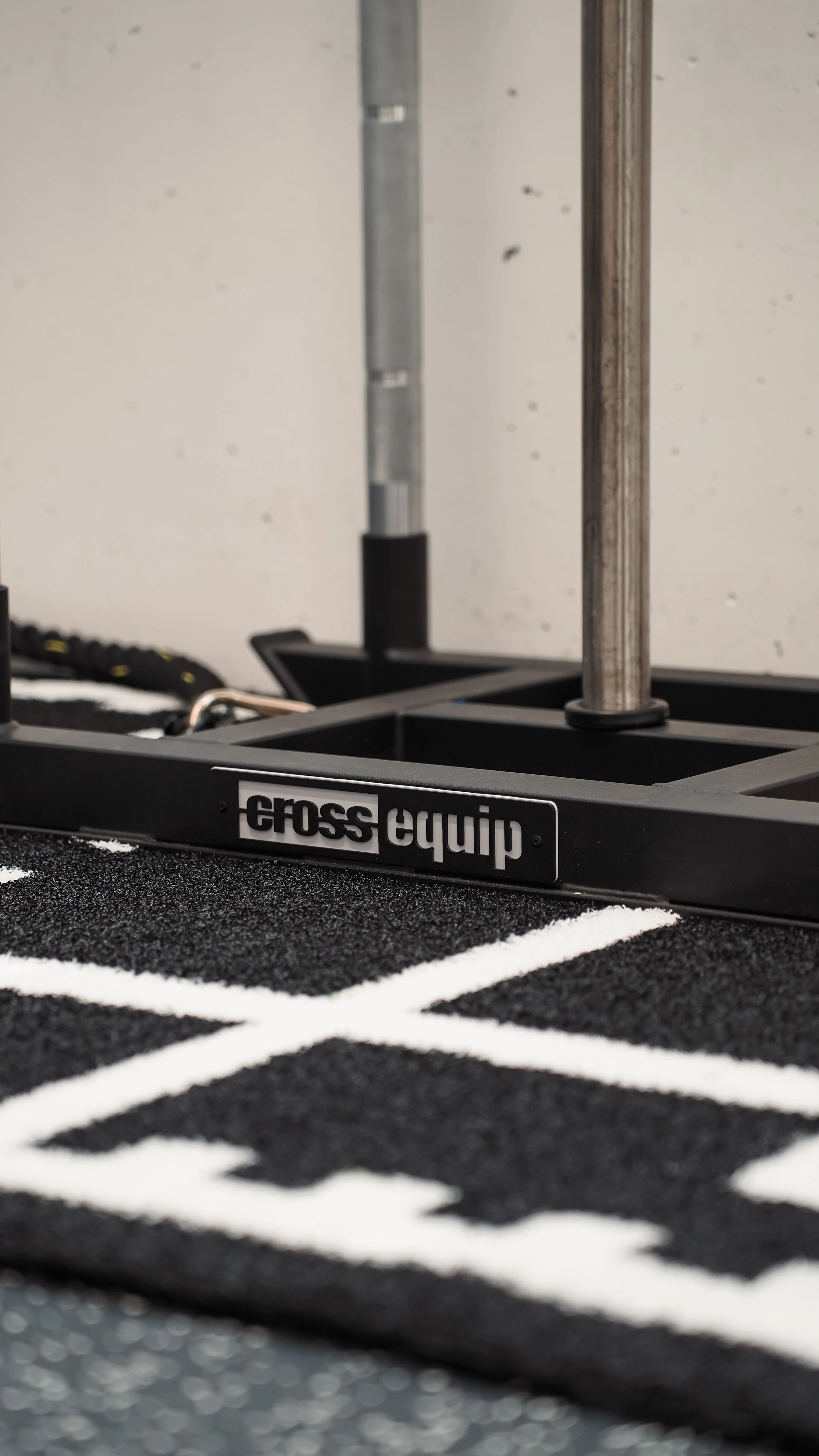 Nahaufnahme eines CrossFit-Rig mit Logo, auf einem schwarzen Gummiboden mit weißen Linien.