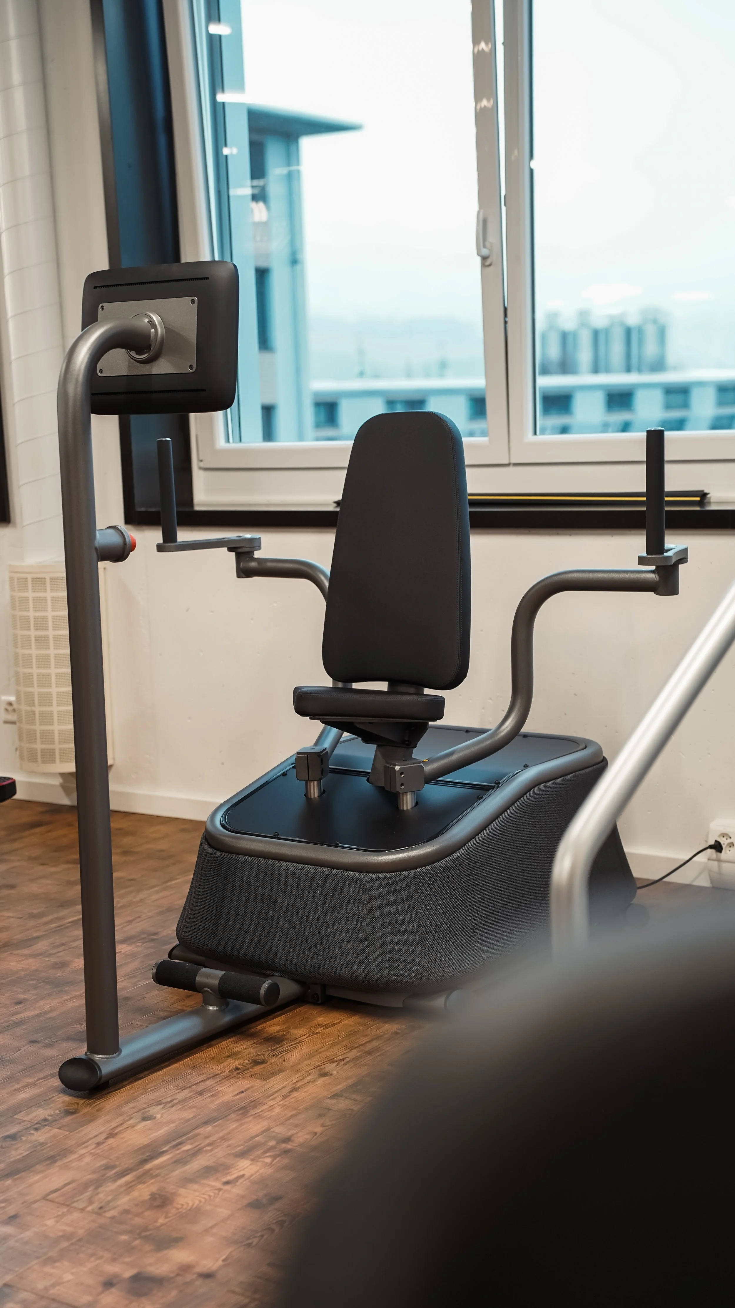 Fitnessgerät in einem Raum mit Holzfußboden und großem Fenster im Hintergrund.