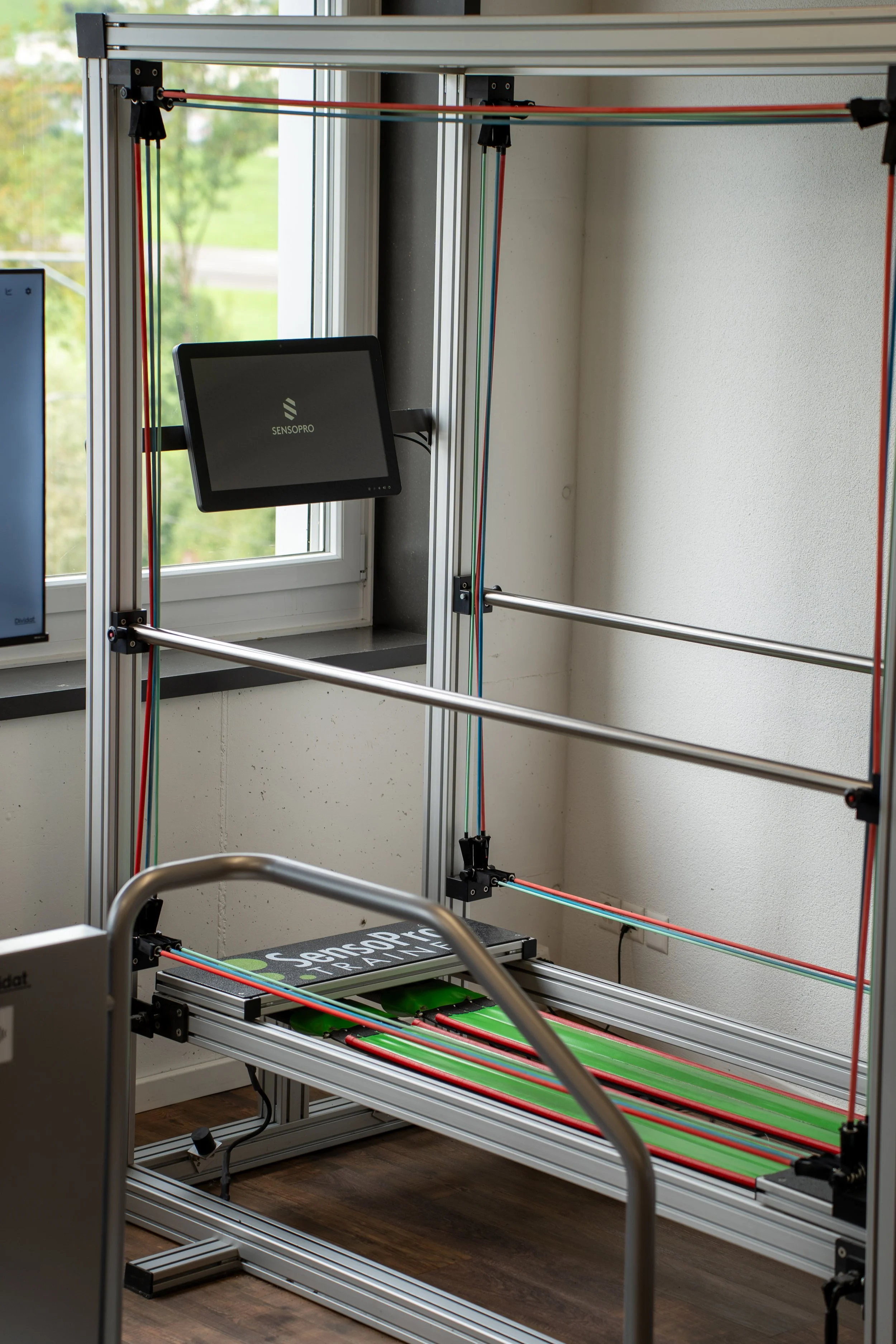 Ein Messgerät für die Trainingsanalyse, ausgestattet mit mechanischen Armen und Sensoren, in einem Raum mit Fenster, vermutlich für Leistungs- oder Bewegungstests.