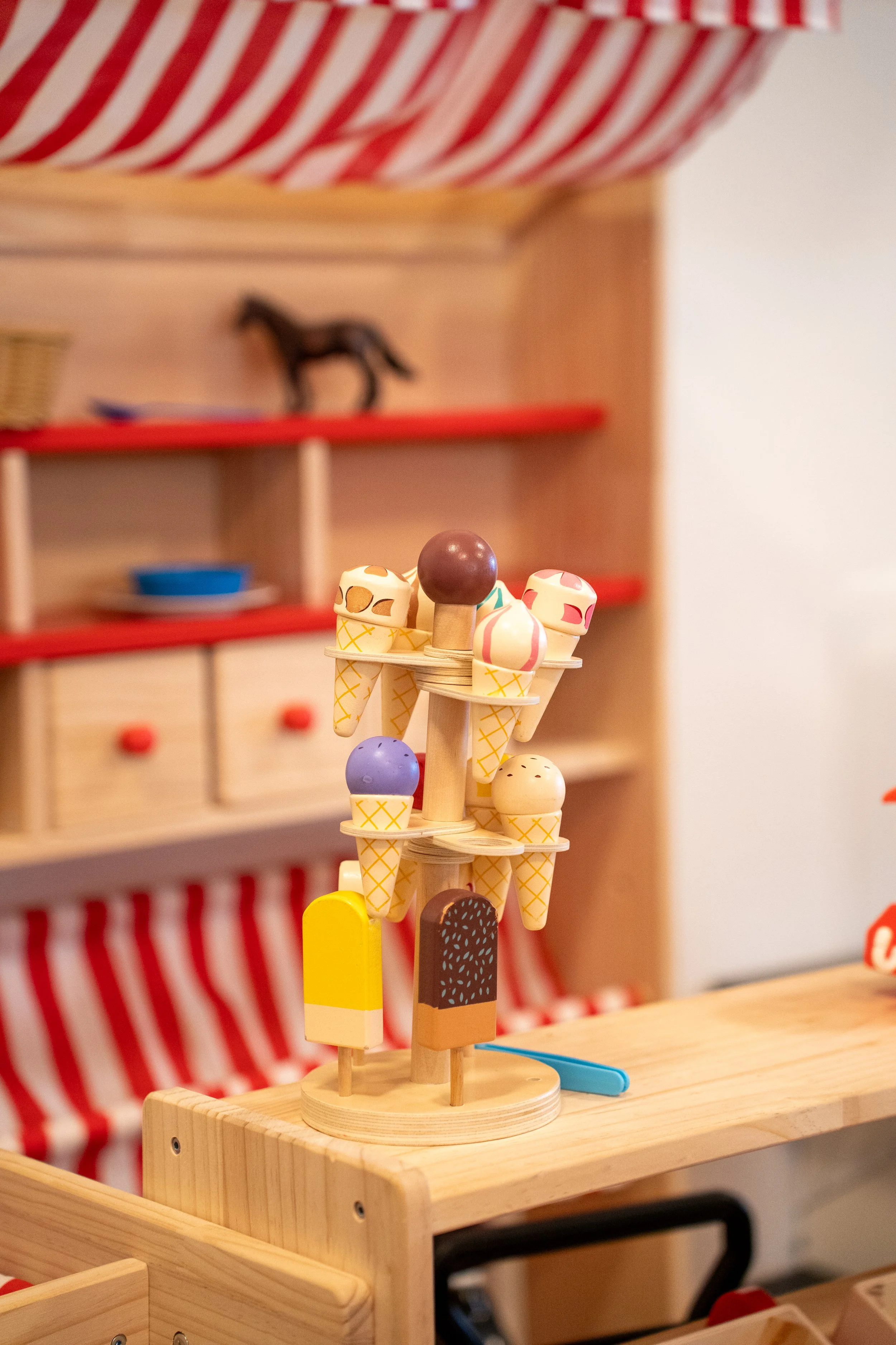 Szenerie eines Spielzeugs, das Eiswaffeln mit bunten Kugeln darstellt, auf einem Holztisch in einem Spielzimmer