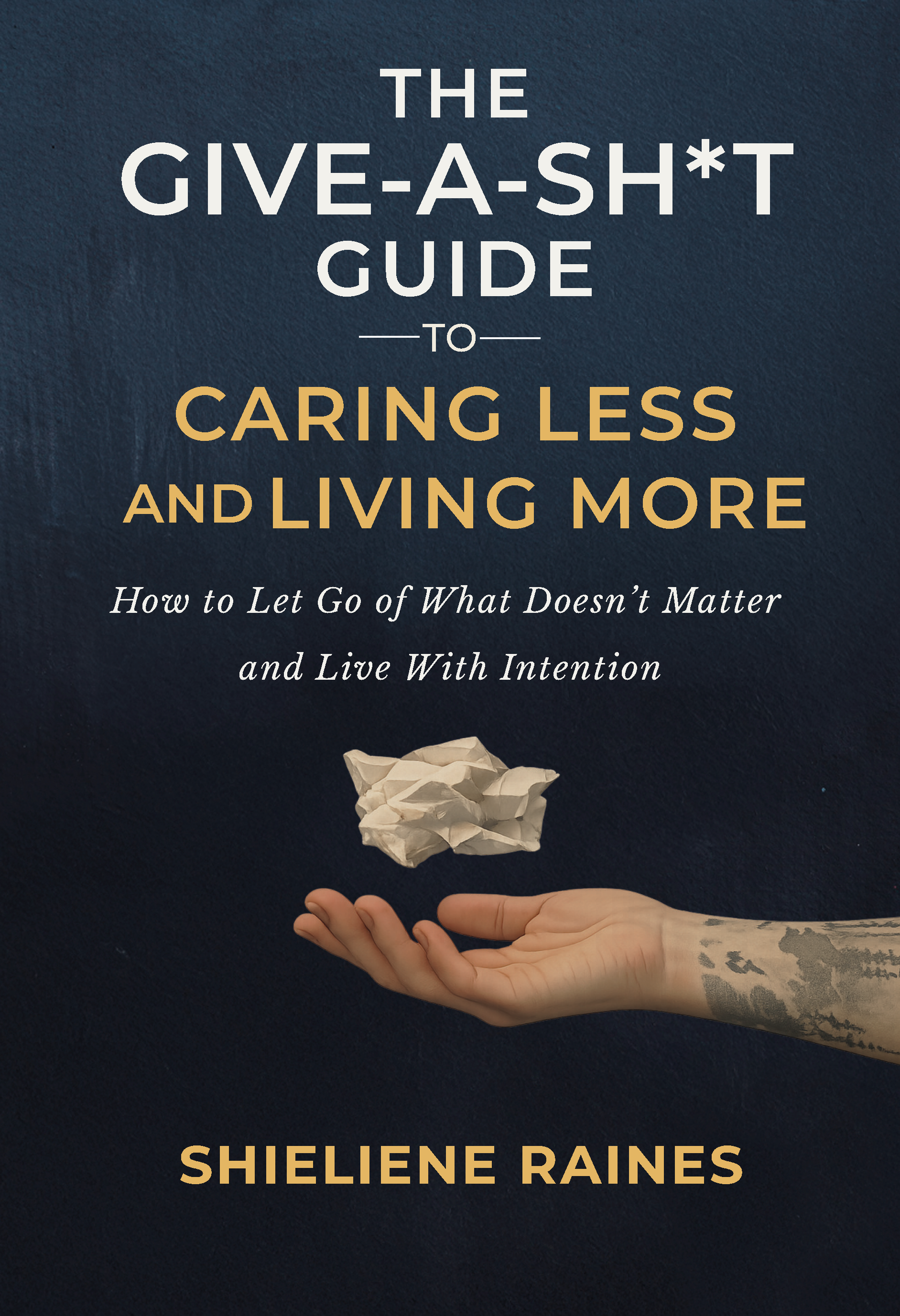 Book cover titled "The Give-A-Sh*t Guide to Caring Less and Living More" by Shielene Raines, featuring a hand with a tattoo holding a crumpled piece of paper against a dark blue background.