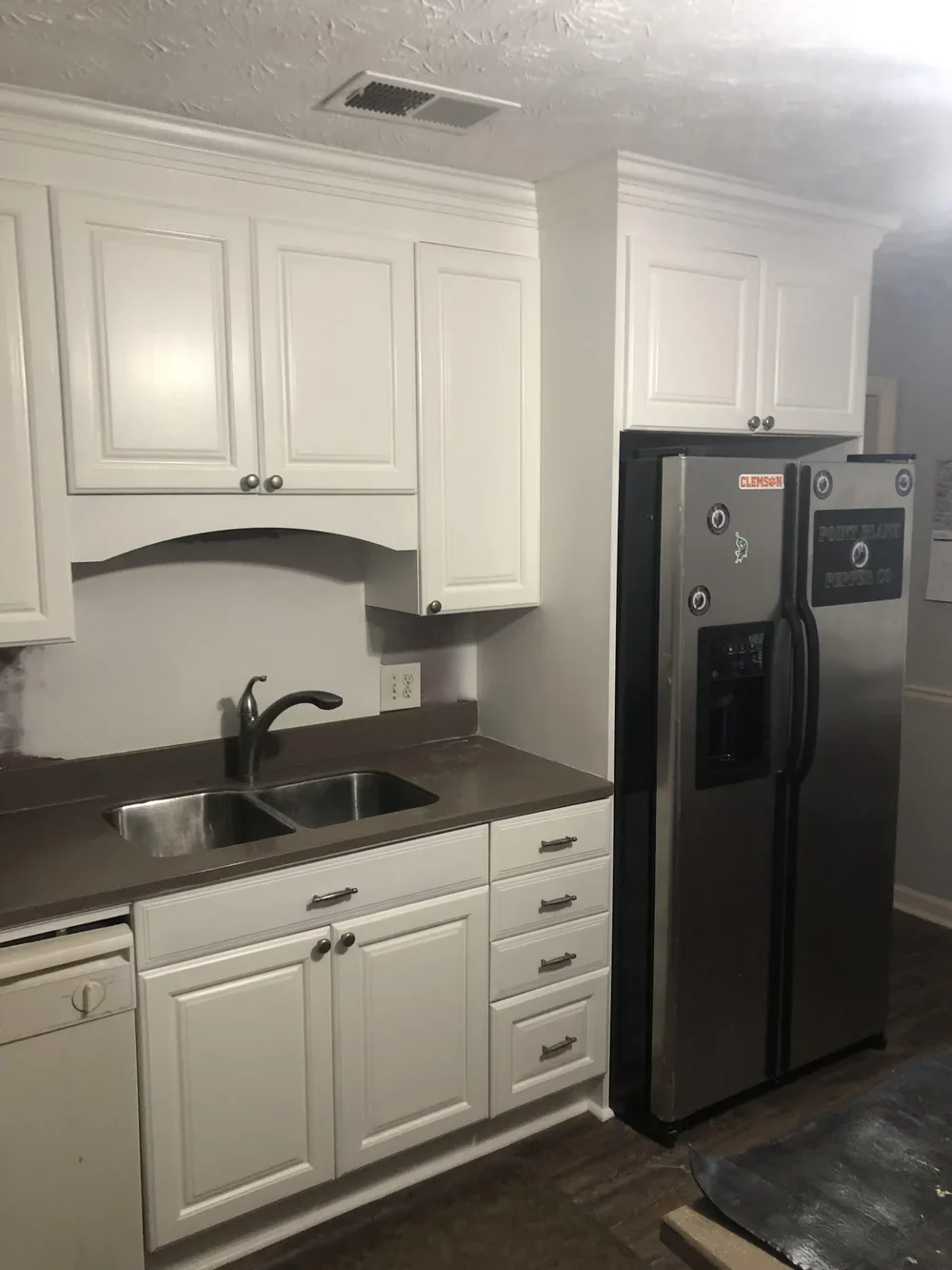 Kitchen with white cabinets, stainless steel double sink, black faucet, and stainless steel refrigerator.