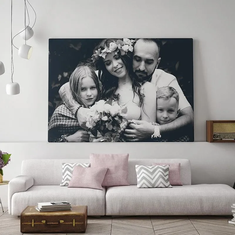 Large black and white family portrait on living room wall showing three children and an adult woman with flower crown. They are smiling and hugging.