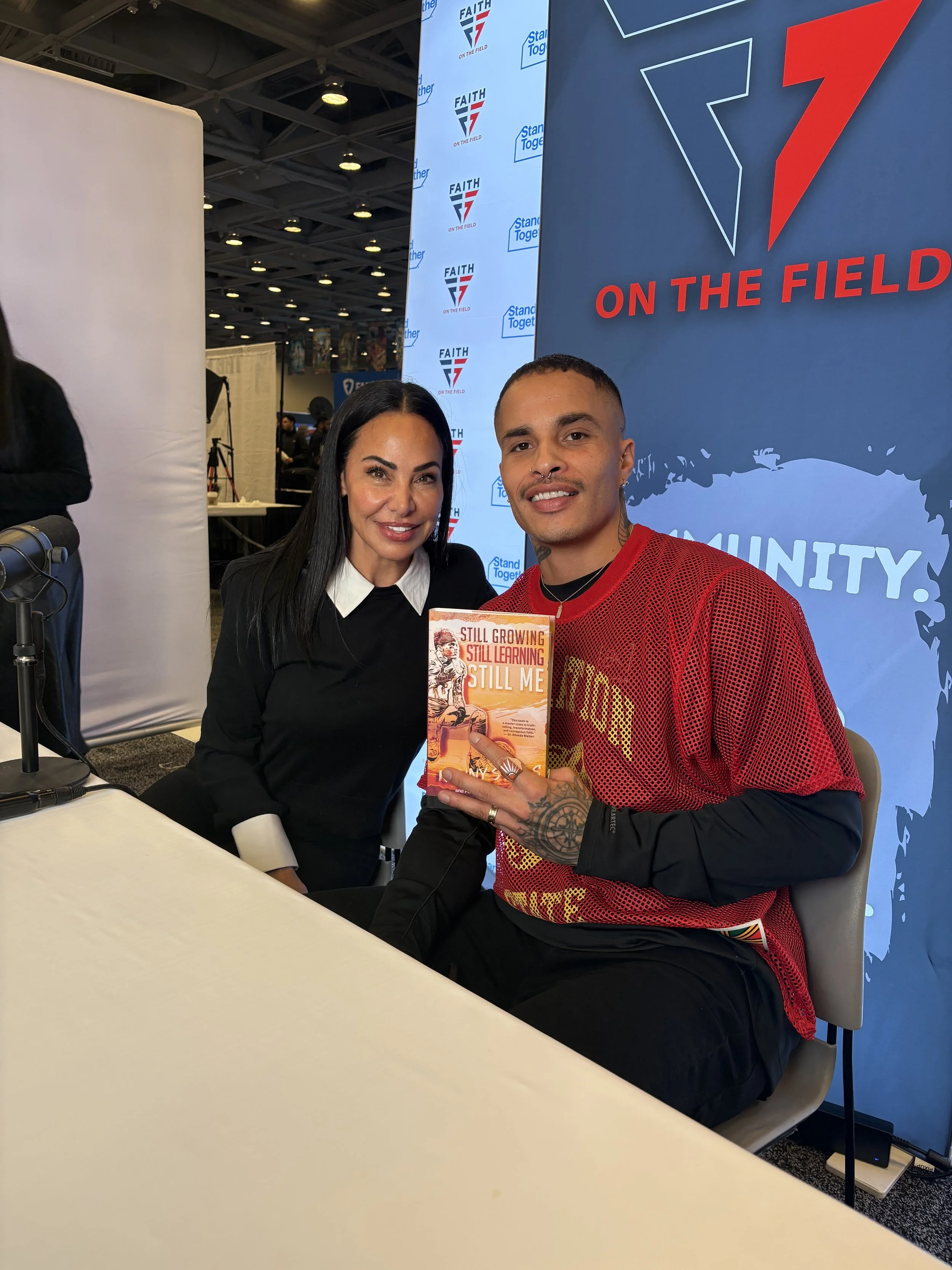 NFL football player Kenny Still with Artem Vale Foundation showing book at Superbowl LX for mental health