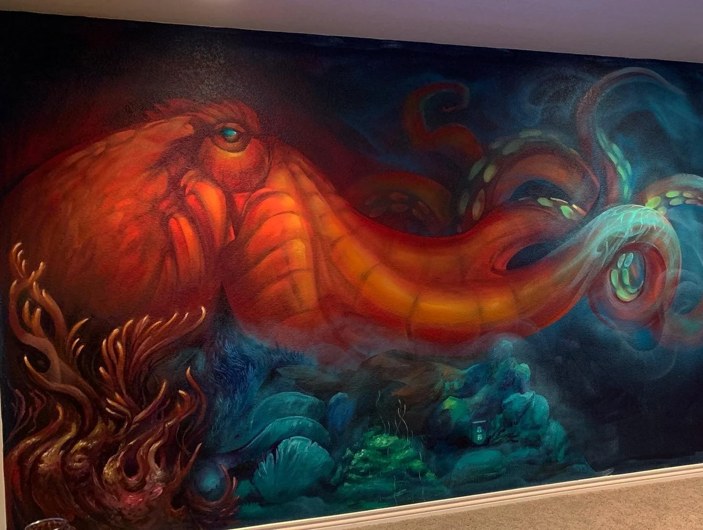 Colorful mural of an octopus with a large head and flowing tentacles, painted in vibrant shades of orange, red, teal, and green.