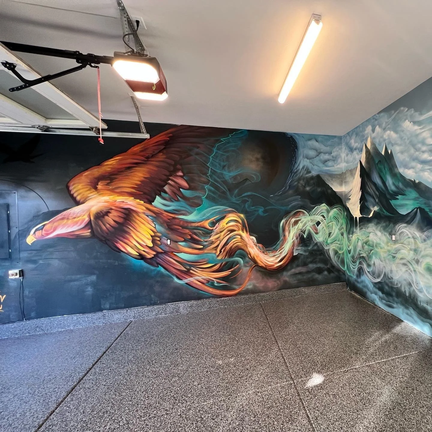 Colorful mural of a phoenix in flight over mountains with swirling smoke and clouds.